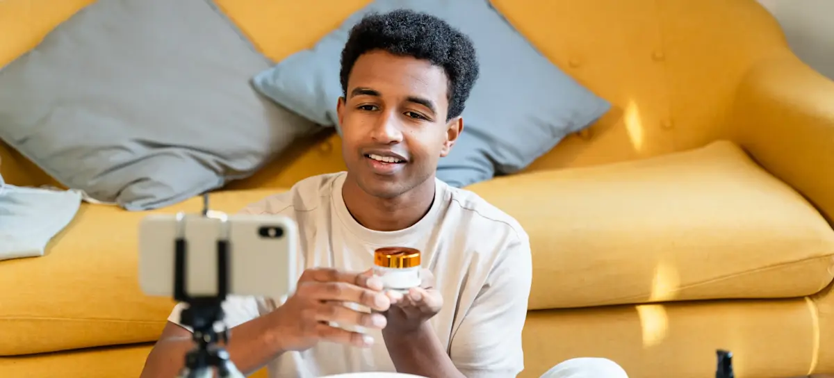 [Featured Image] A UGC creator reviews skincare products while recording themselves on a smartphone in a home setting to create digital content.