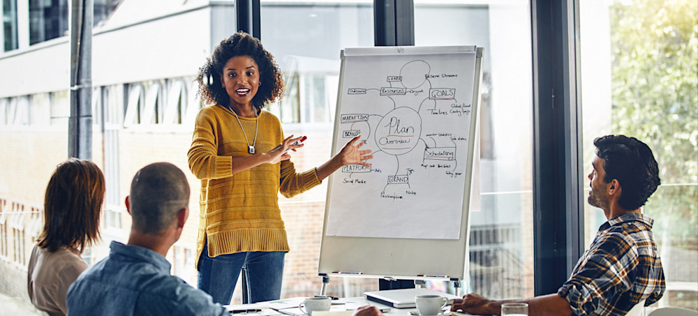 [Feature Image] A learner delivers a presentation to a small group as part of their master’s in marketing degree programme. 