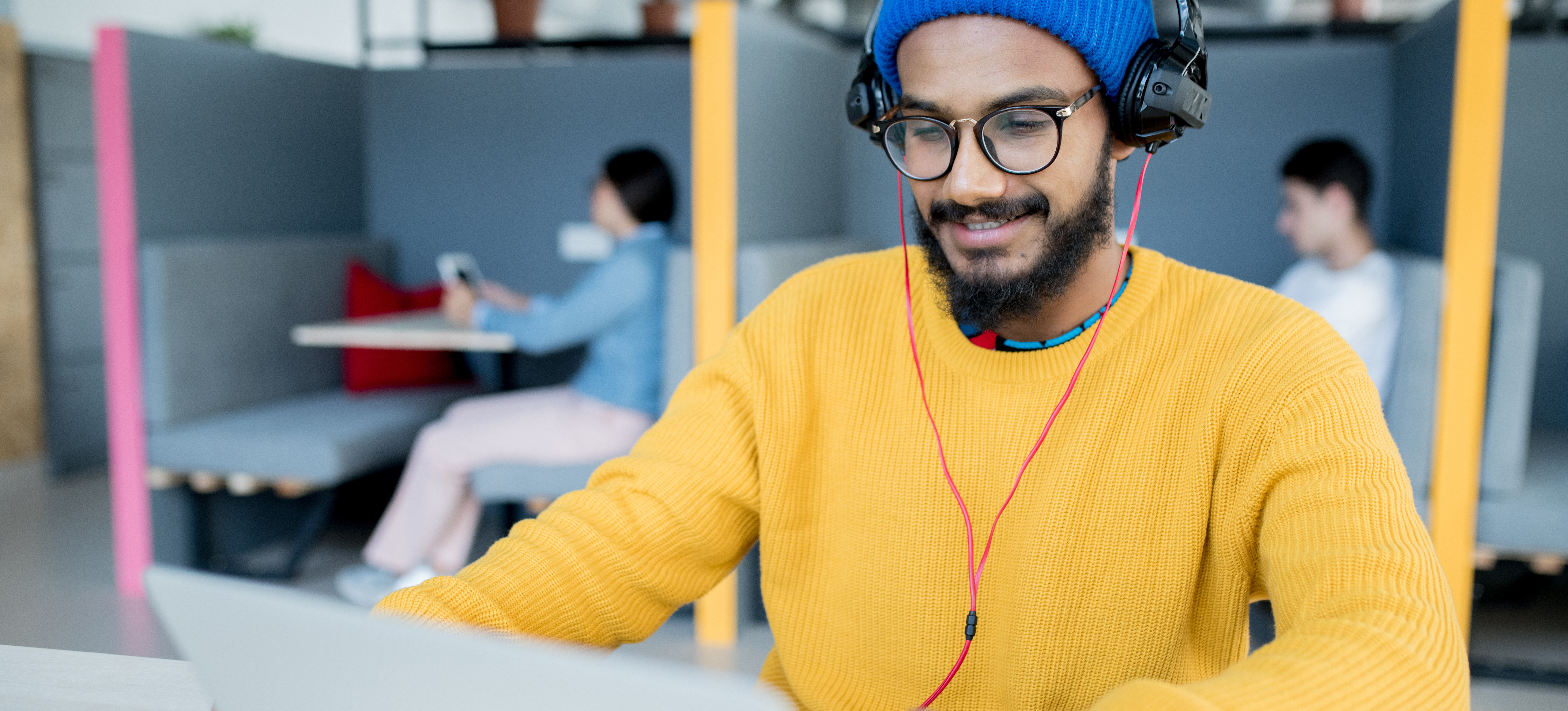 [Featured Image] A person in a yellow sweater types on a laptop in a co-working space.