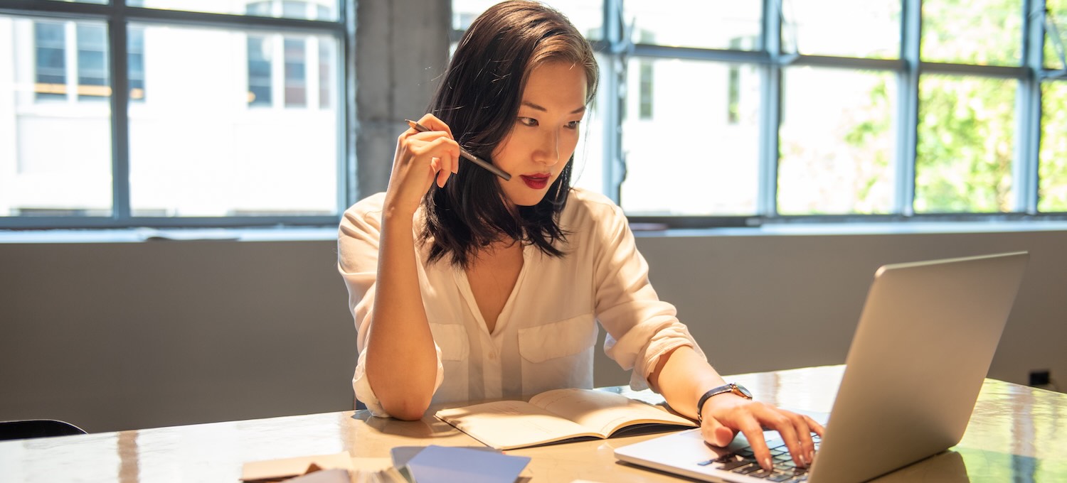 [Featured Image] A certified management accountant studies on a laptop in an office.