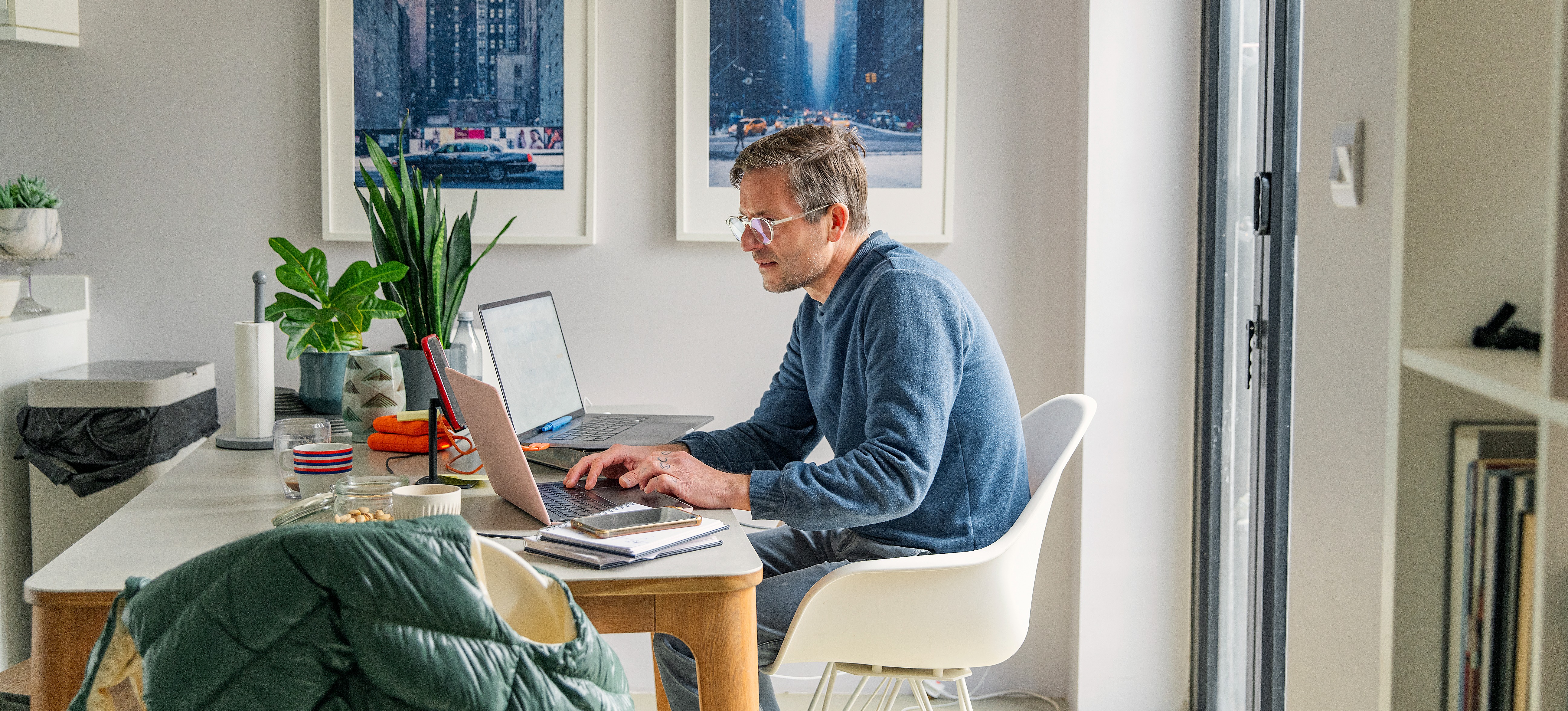 [Featured Image] A man sits at his table at home with his laptop. He is searching web developer salary for his future career.
