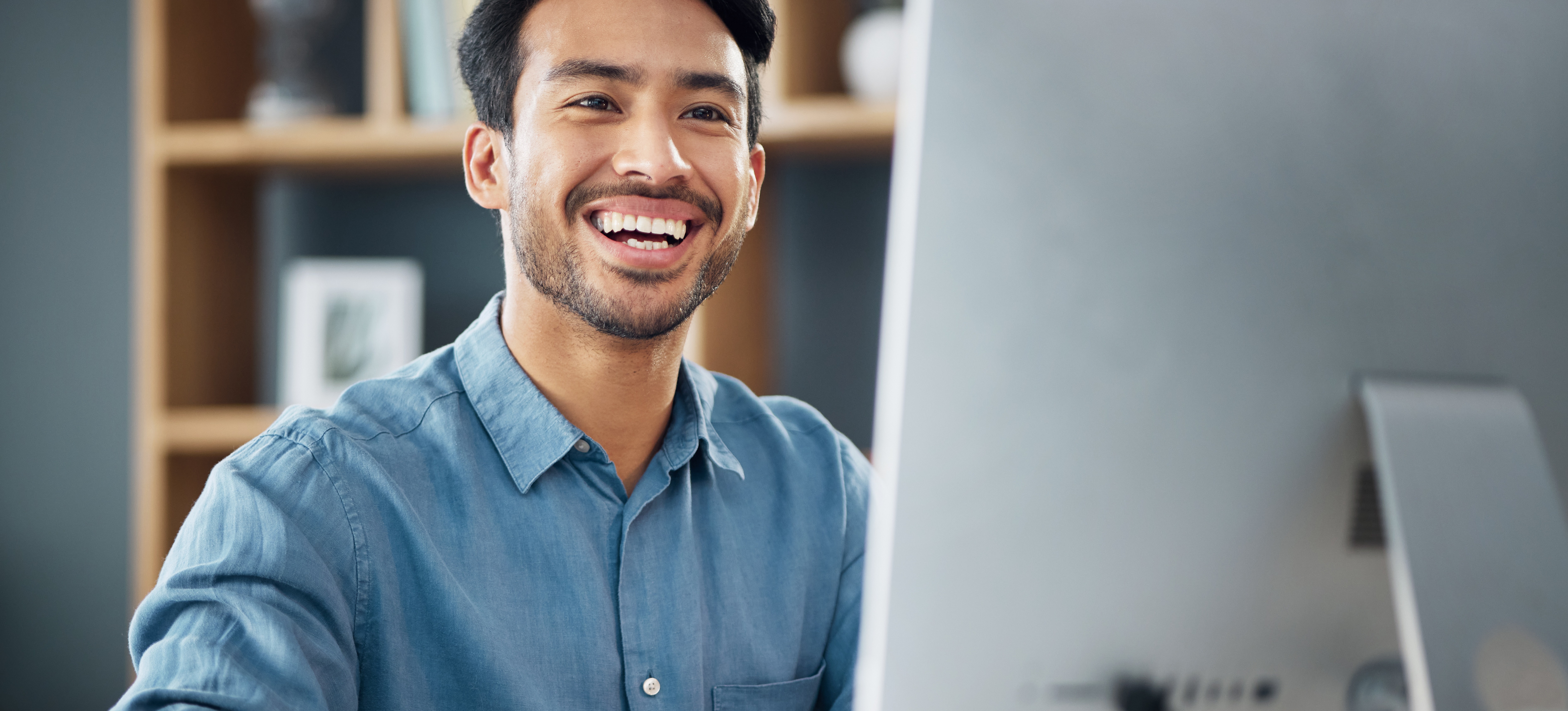 [Feature Image] An AI user experiments with Anthropic Claude and smiles as they become more familiar with the program on their desktop computer. 
