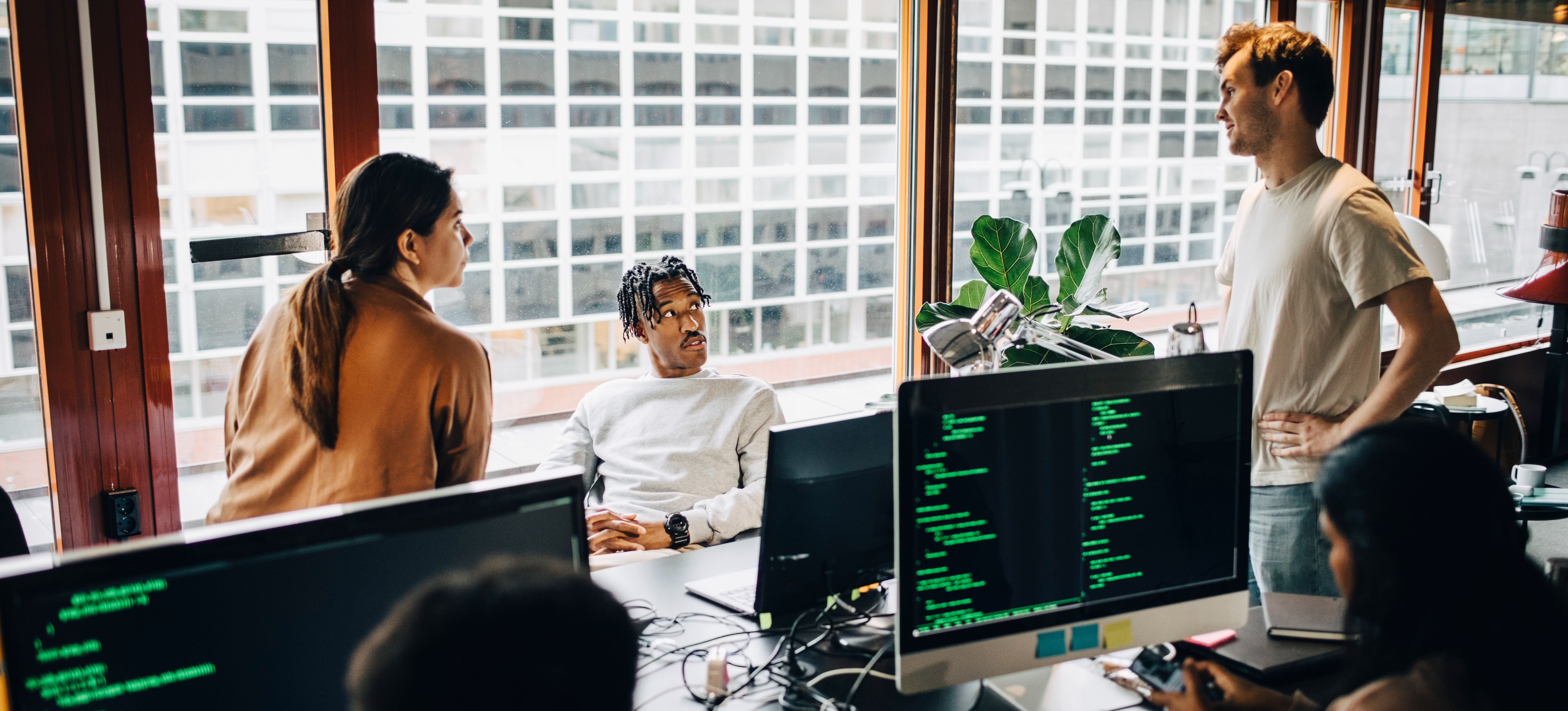 [Featured Image] Cybersecurity professionals working together at various CISSP jobs in a tech startup office.
