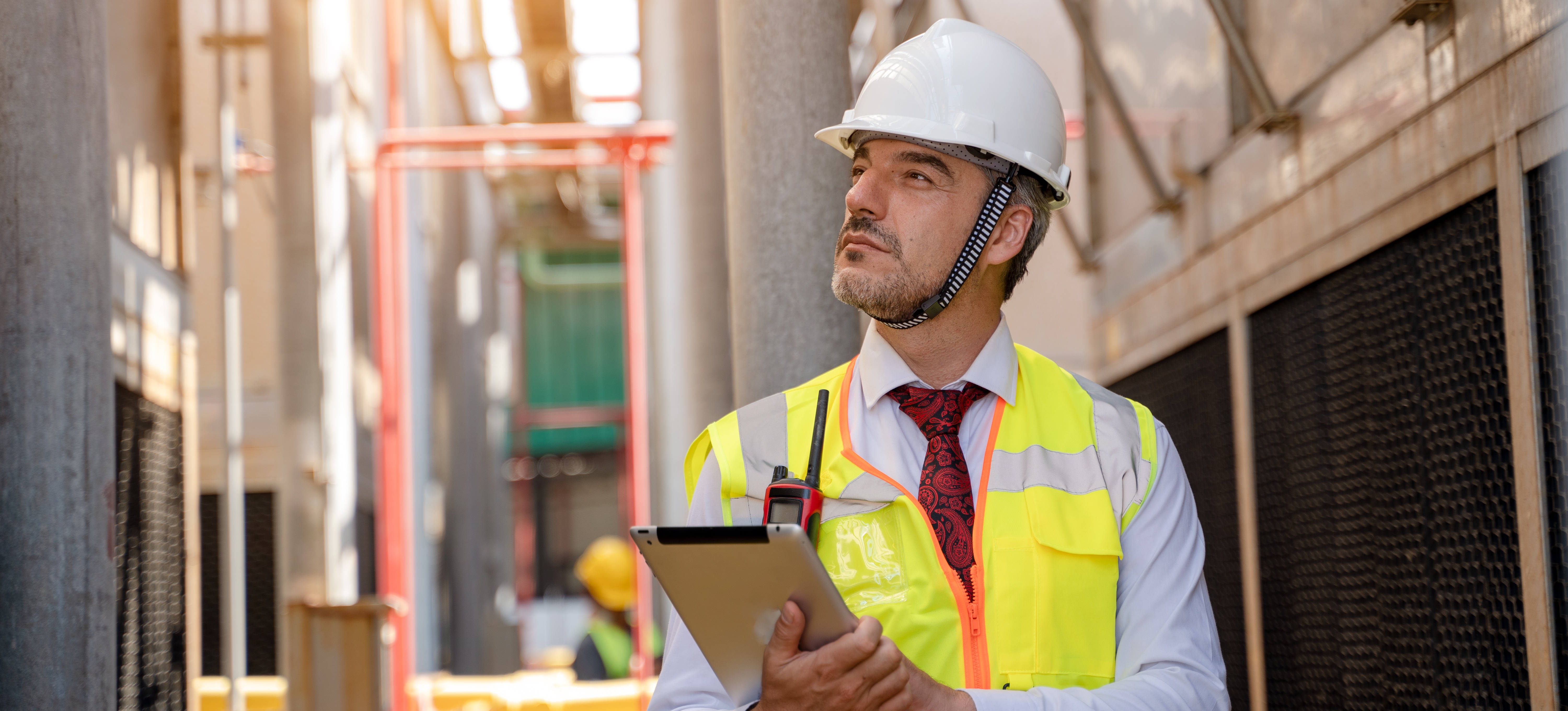 [Featured image] A building inspector wearing a hard hat holds a clipboard as they inspect a building.
