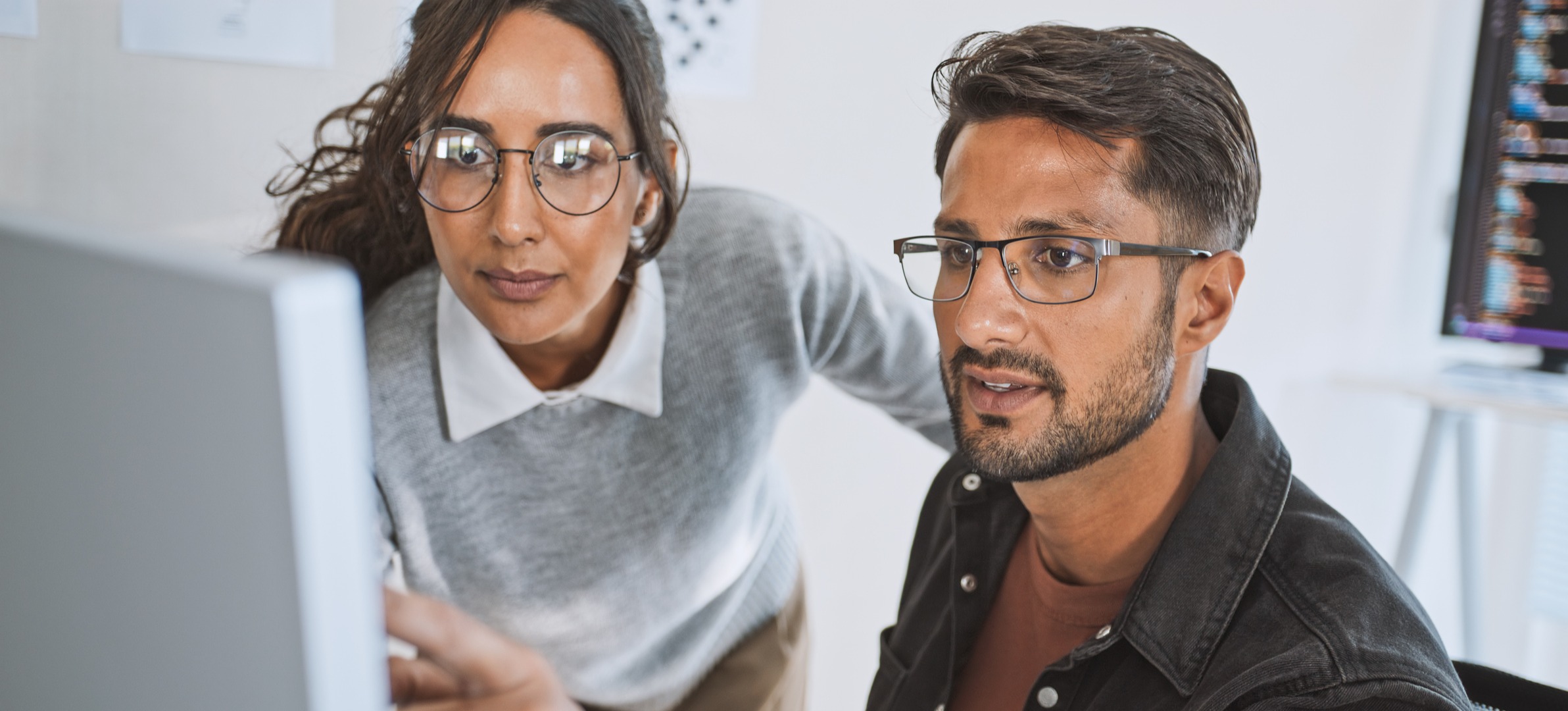 [Featured image] An IT manager helps her colleague solve a network issue on a desktop computer.