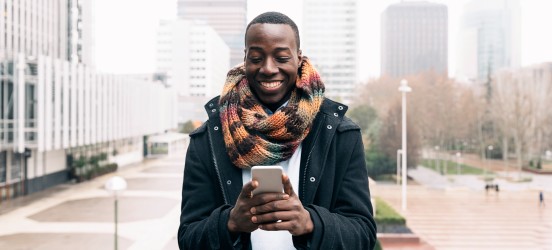 [Featured Image] A business person uses a smartphone outdoors, learning how to write a LinkedIn recommendation.