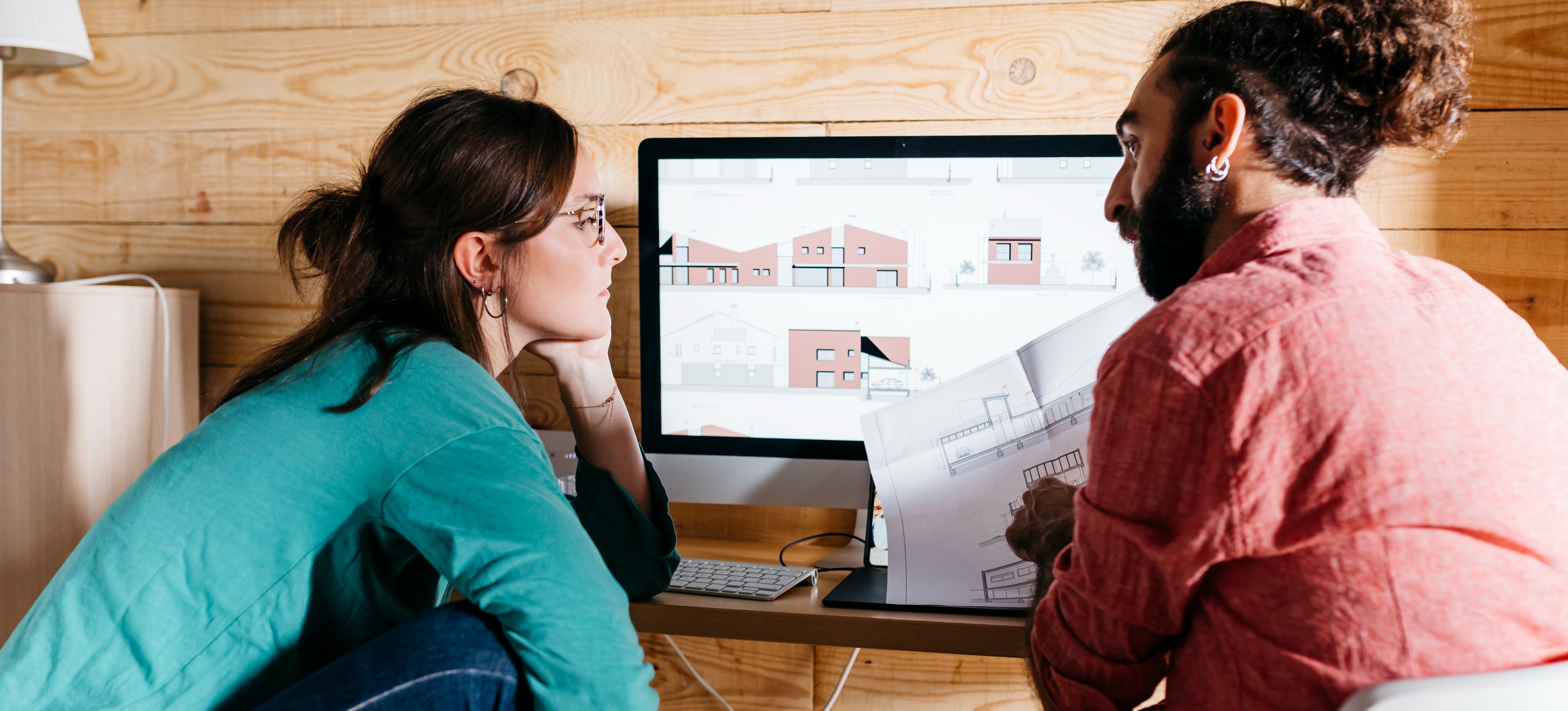[Featured Image] After learning what is cad as part of their training, two young architects sit at a laptop and work on building designs.
