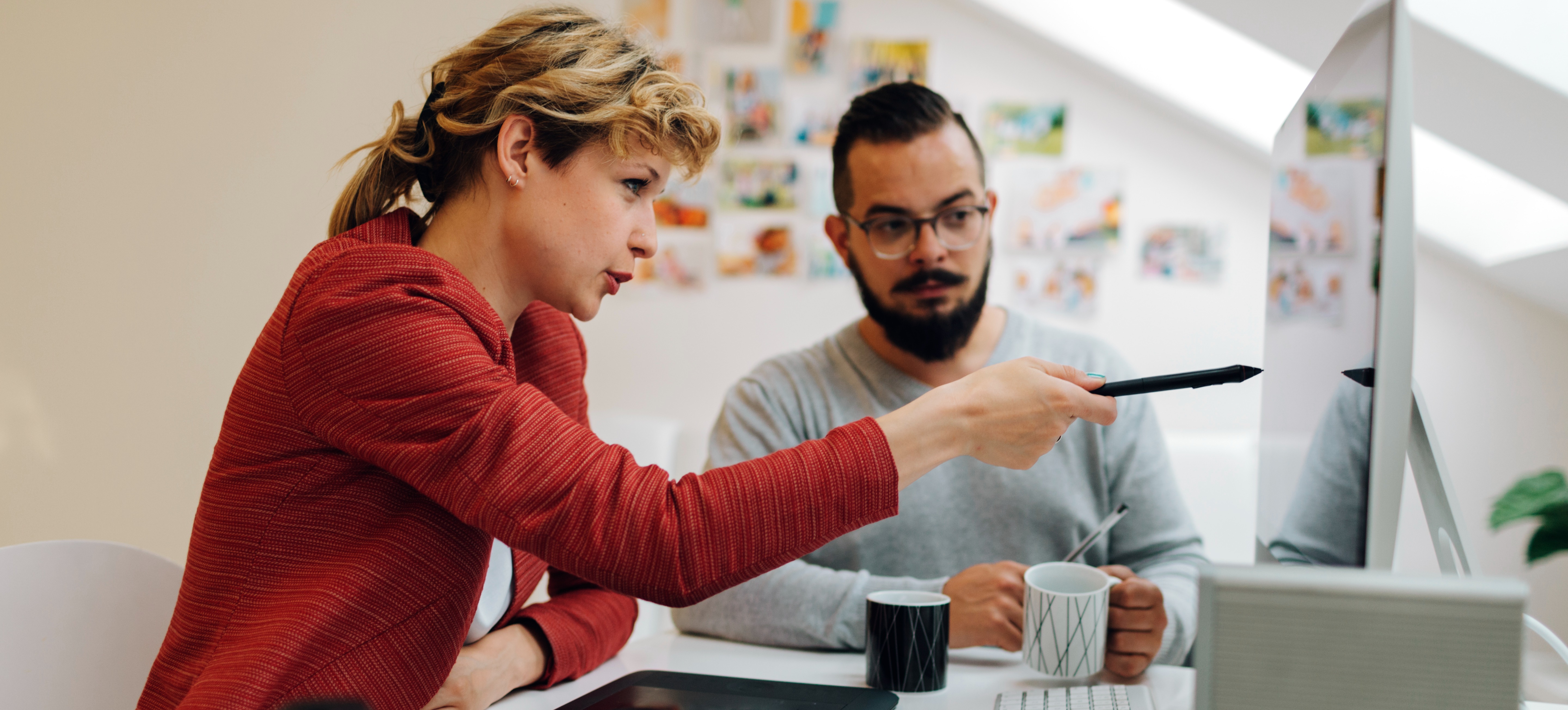 [Featured Image] Two graphic designers working together at a computer desk.
