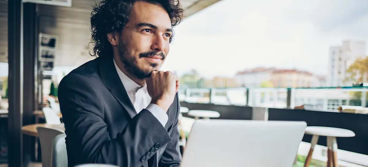 [Featured Image]:  A person wearing a dark suit, sitting in front of a laptop computer, using information and tools to build a memory palace. 