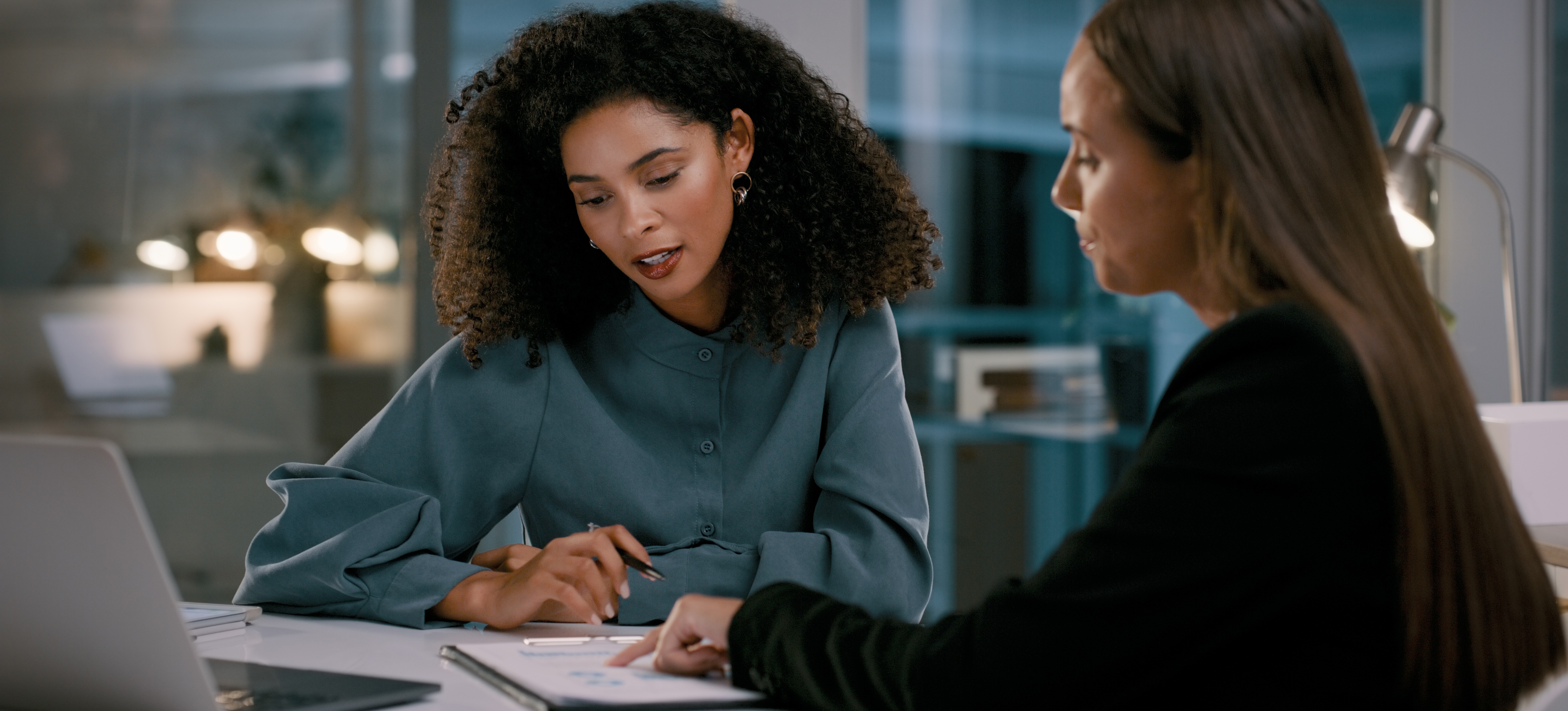 [Image en vedette] Un superviseur discute d'un plan de formation avec son employé alors qu'ils regardent tous deux un bloc-notes et un ordinateur portable, assis dans un bureau.