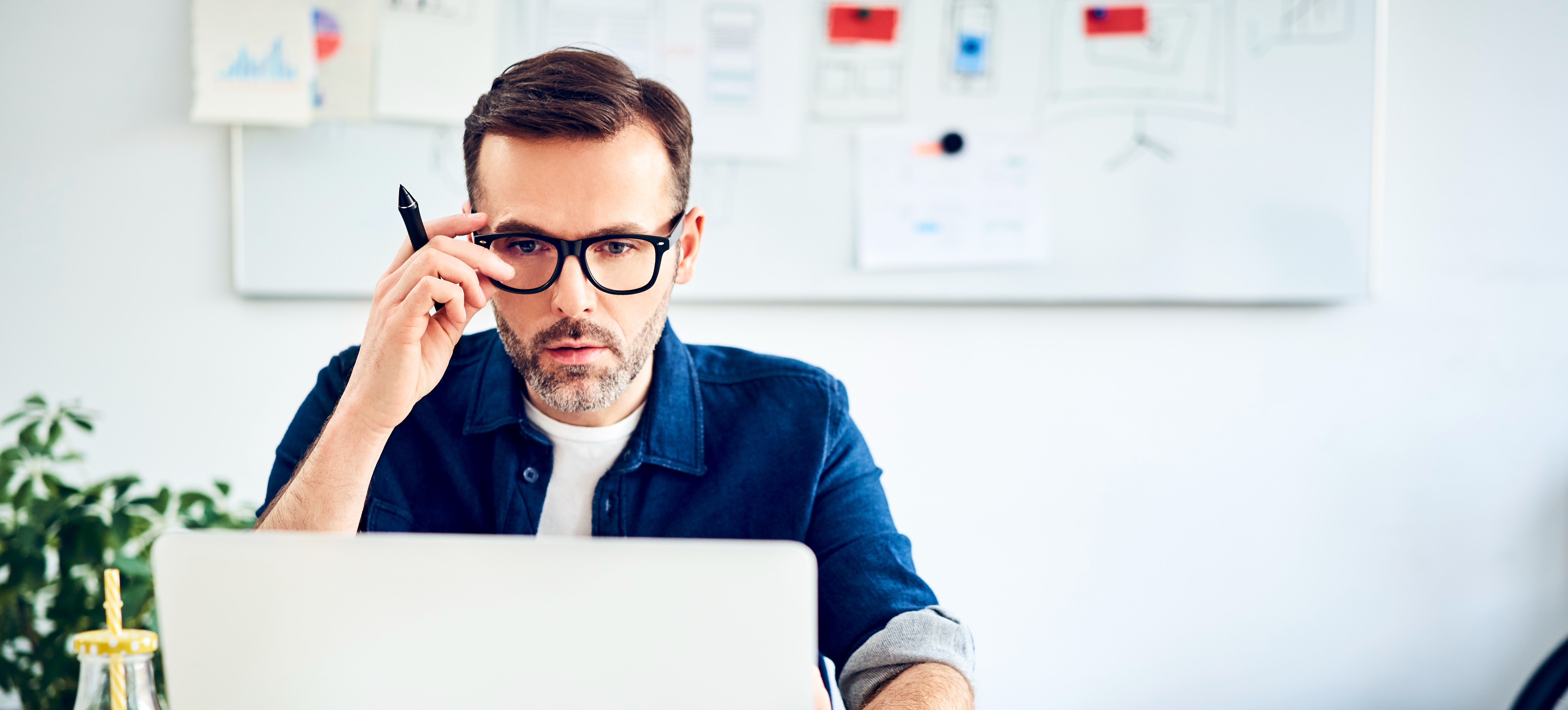 [Featured Image] A DevOps engineer adjusts their glasses while looking at a laptop.