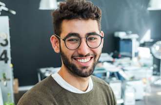 [Featured image] A project manager stands in an office, smiling.