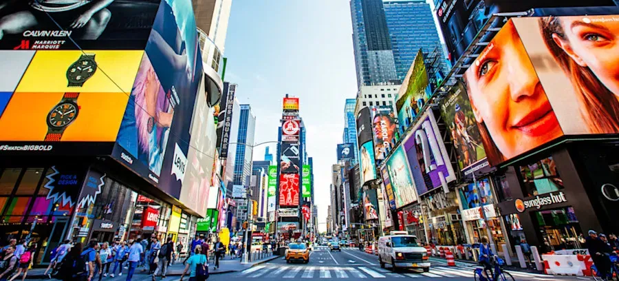 [Featured Image] AI advertising is displayed on numerous billboards that line a busy street in Times Square.
