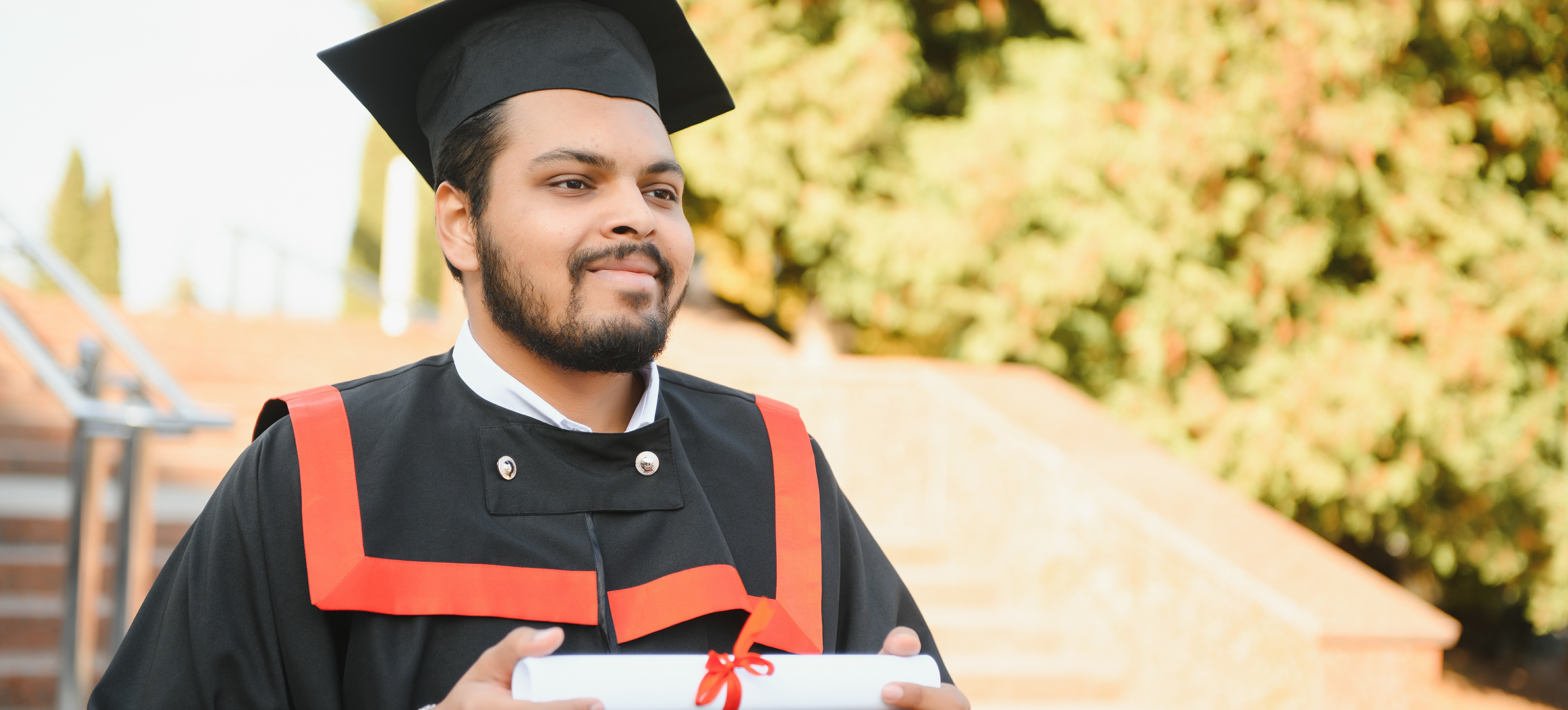 [Featured Image]: A graduate in a cap and gown smiles as they reflects on earning a PhD.
