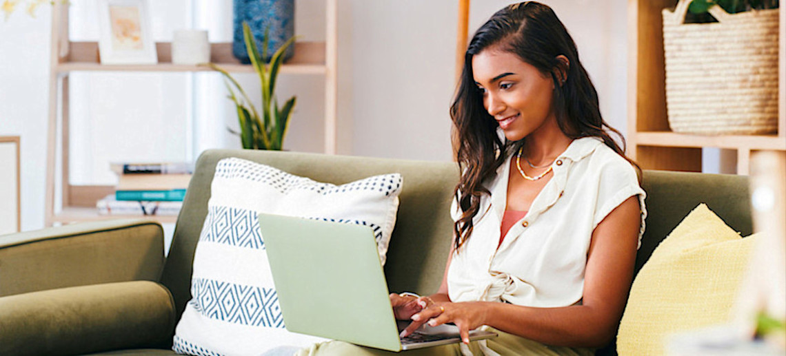 [Featured Image] A young learner sits on a couch at home and uses a laptop to research and determine if they are eligible for lateral entry in BTech. 
