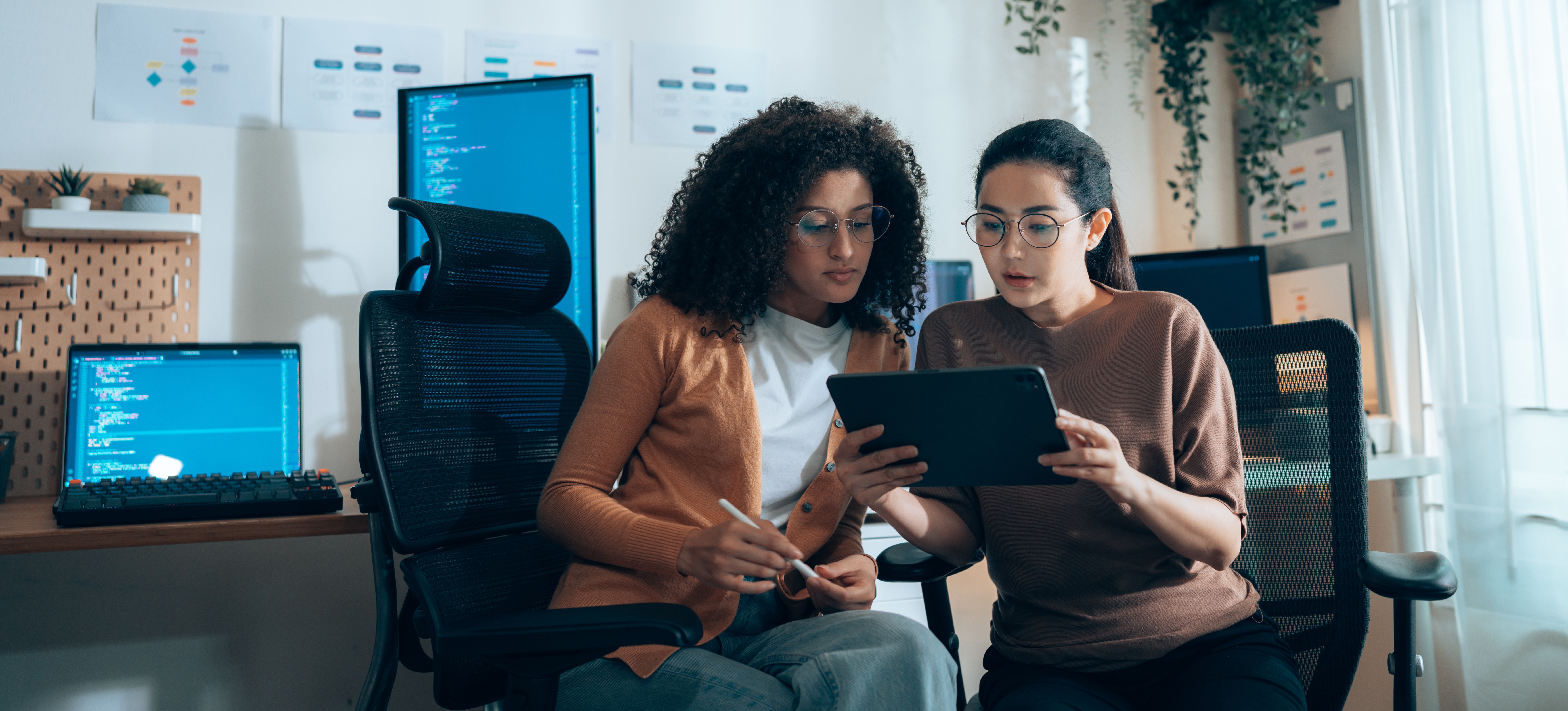 [Featured image] Two finance professionals use data annotation in machine learning while looking at a tablet and sitting at their desks with multiple computer screens in the background.
