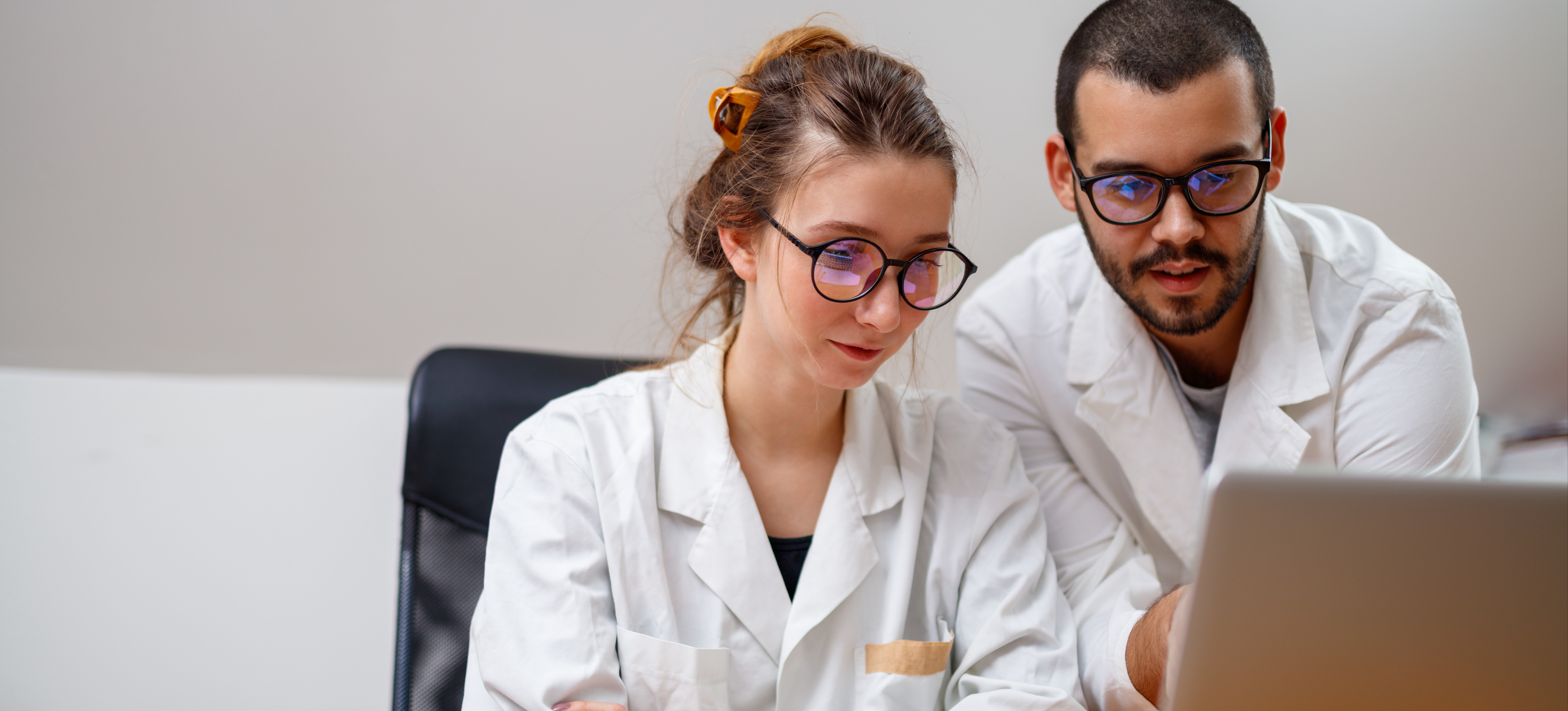[Featured Image] Two neural engineers study the nervous system on a laptop in a lab. 