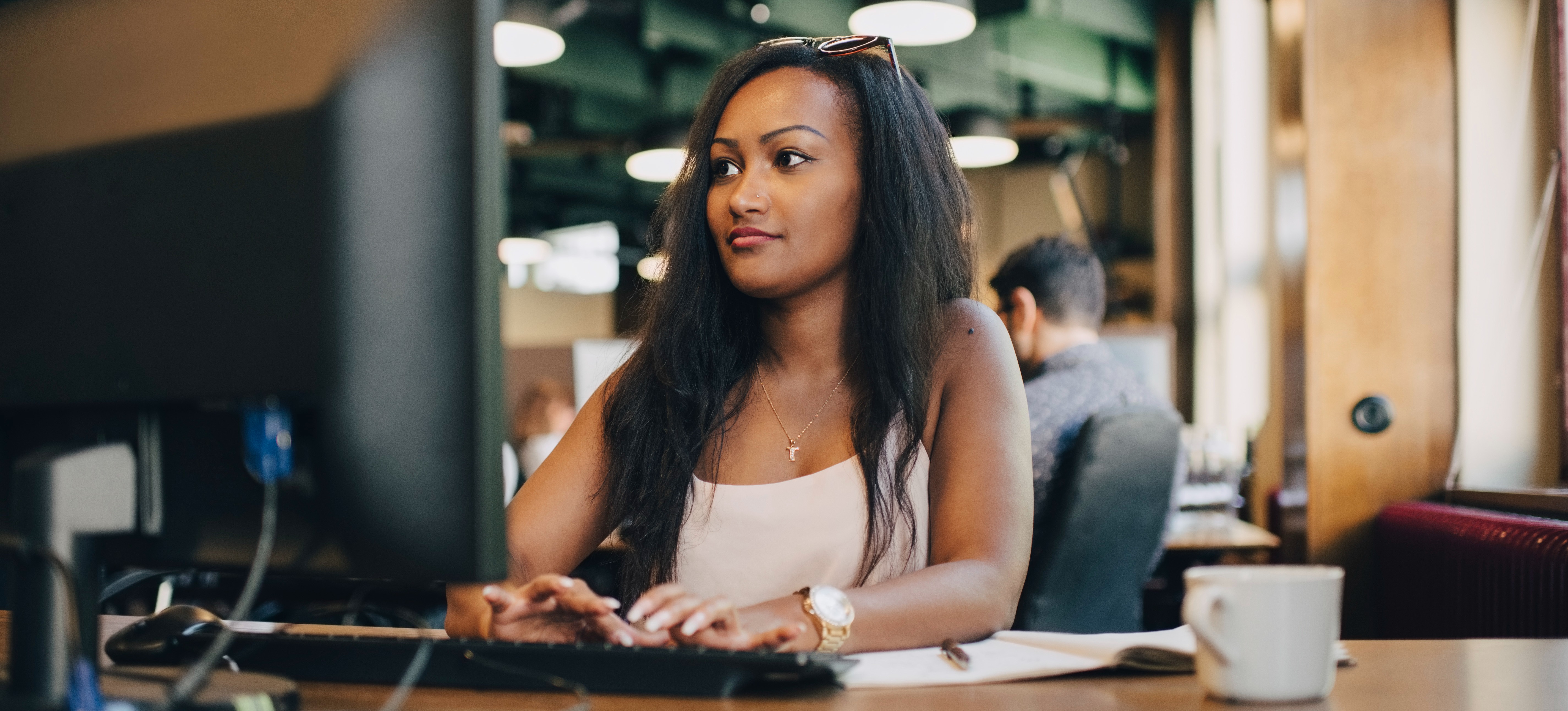 [Featured Image] A professional works in an office at a desktop computer. 
