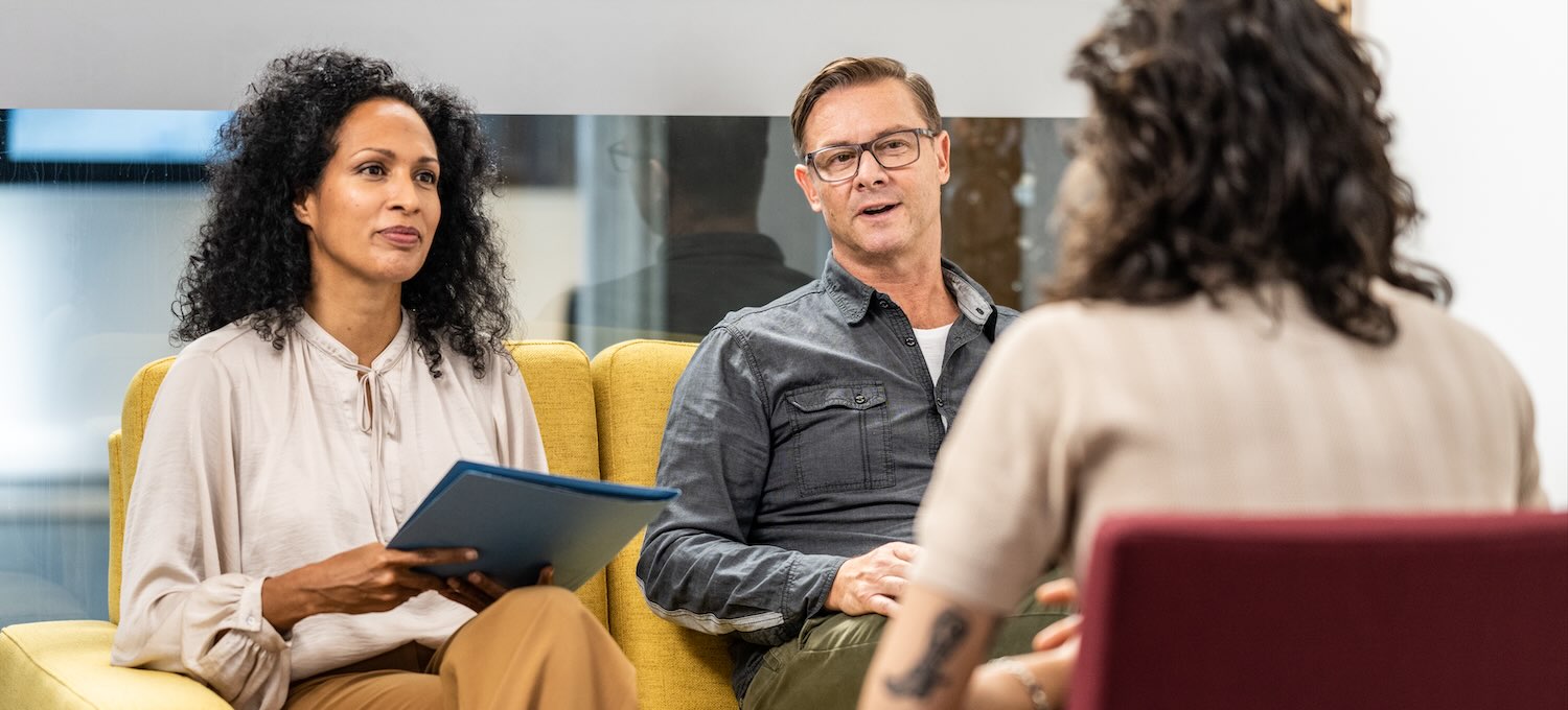[Featured Image] Two employers sit with a prospective hire to discuss the process and outlook of starting this new job