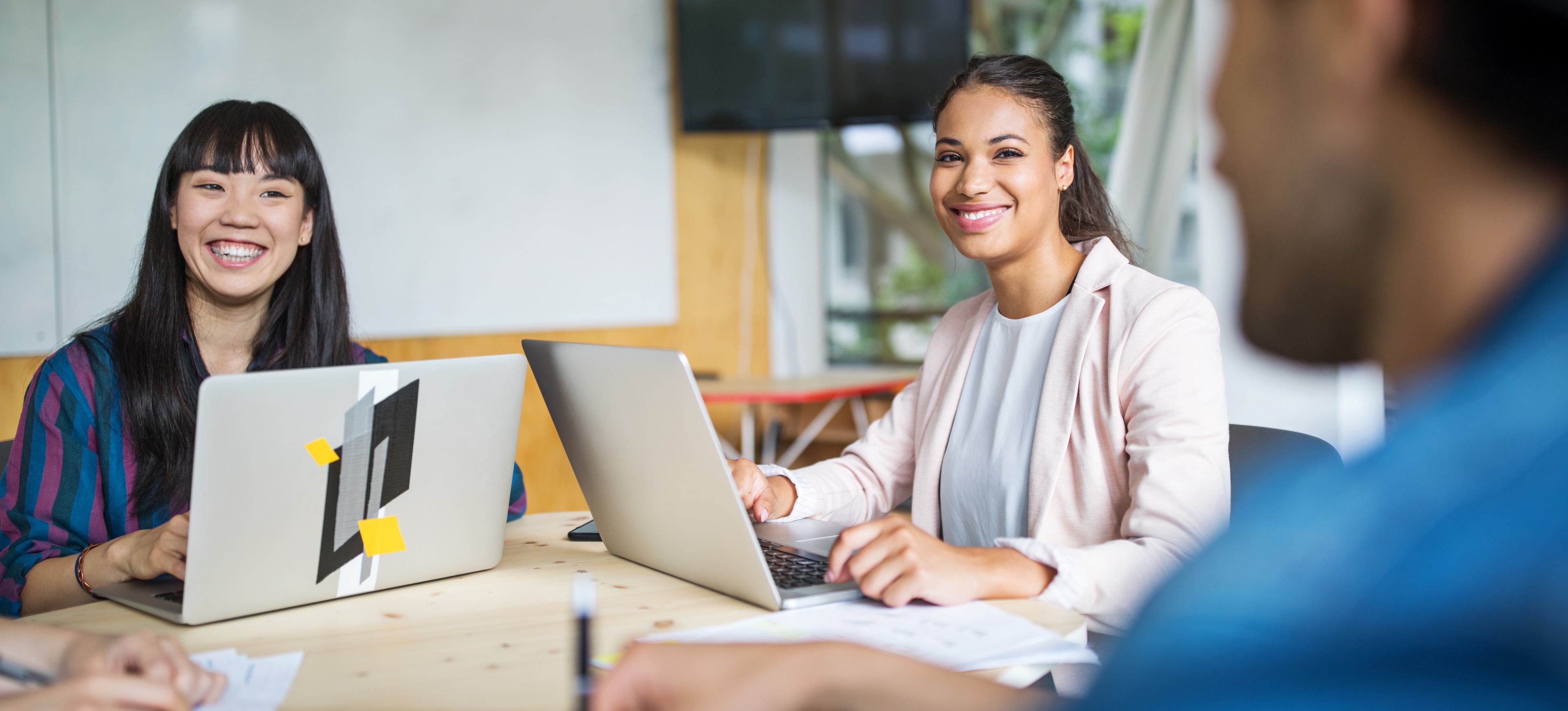 [Featured Image] A team sits at a conference table, working on individual laptops with project management tools.