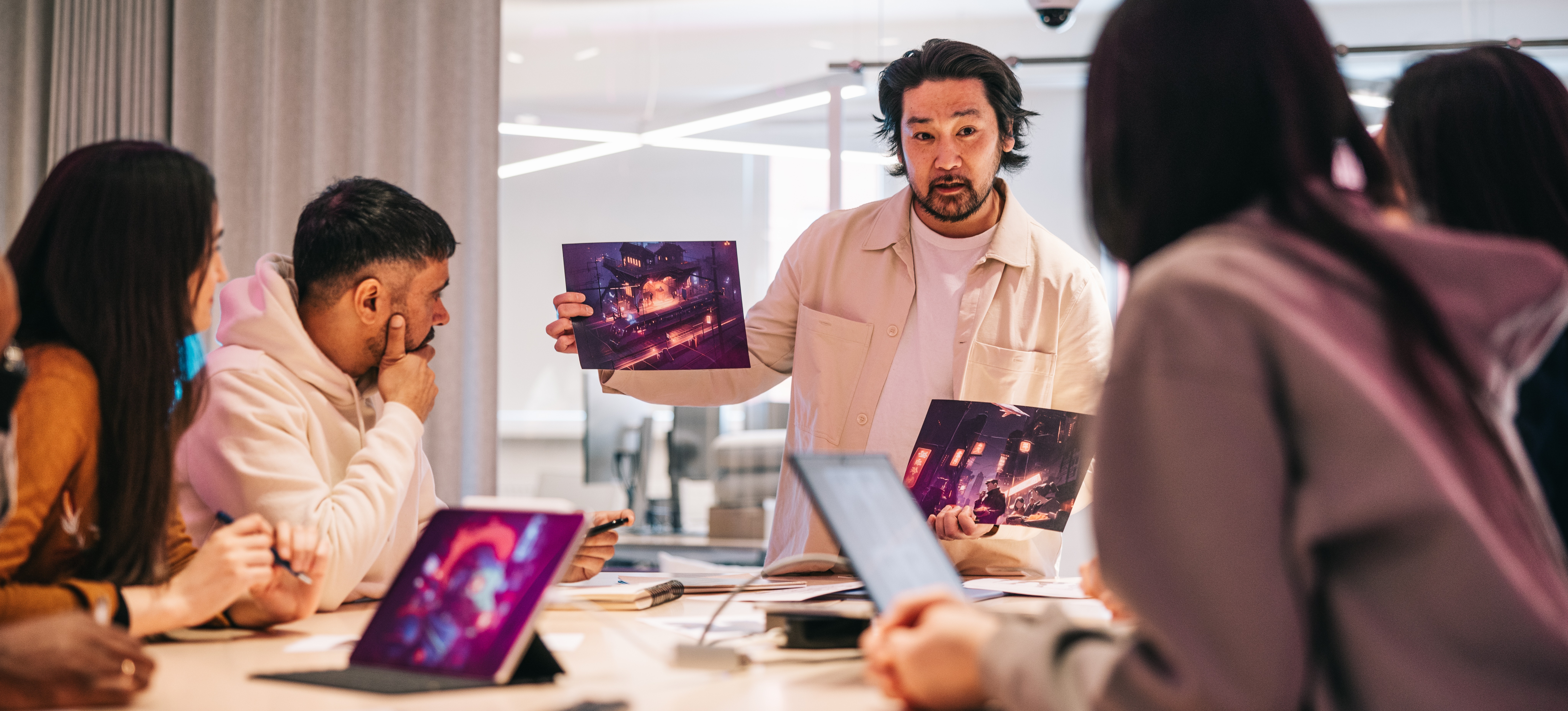 [Featured Image] A man working for a game developer salary stands in front of colleagues and presents imagery from a video game.
