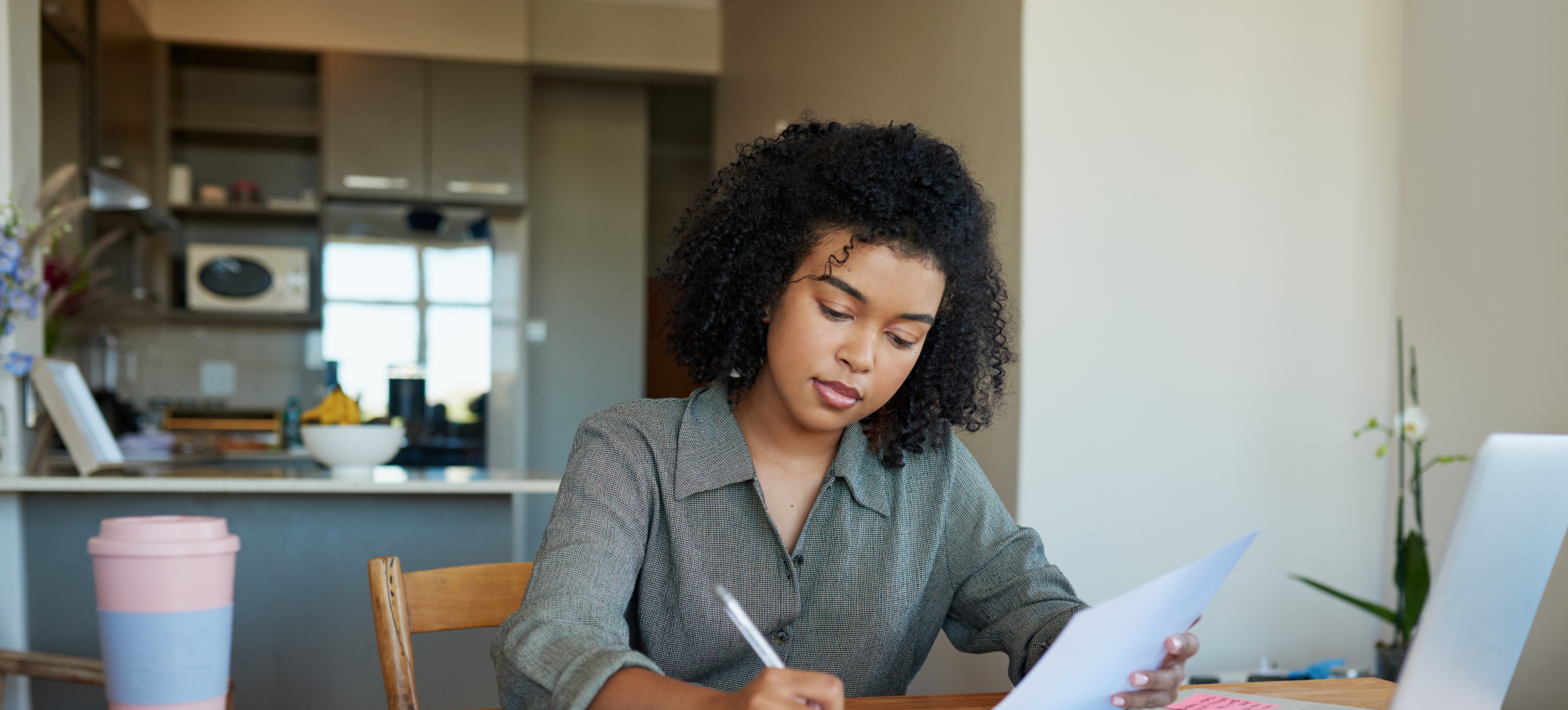 [Featured Image] A job applicant sits at their home desk with a pen in hand and works on their combination resume.