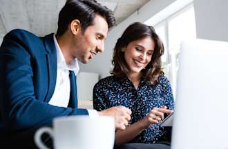 [Featured image] Two people working on an affiliate marketing campaign collaborate at a desk with a tablet and a laptop computer.