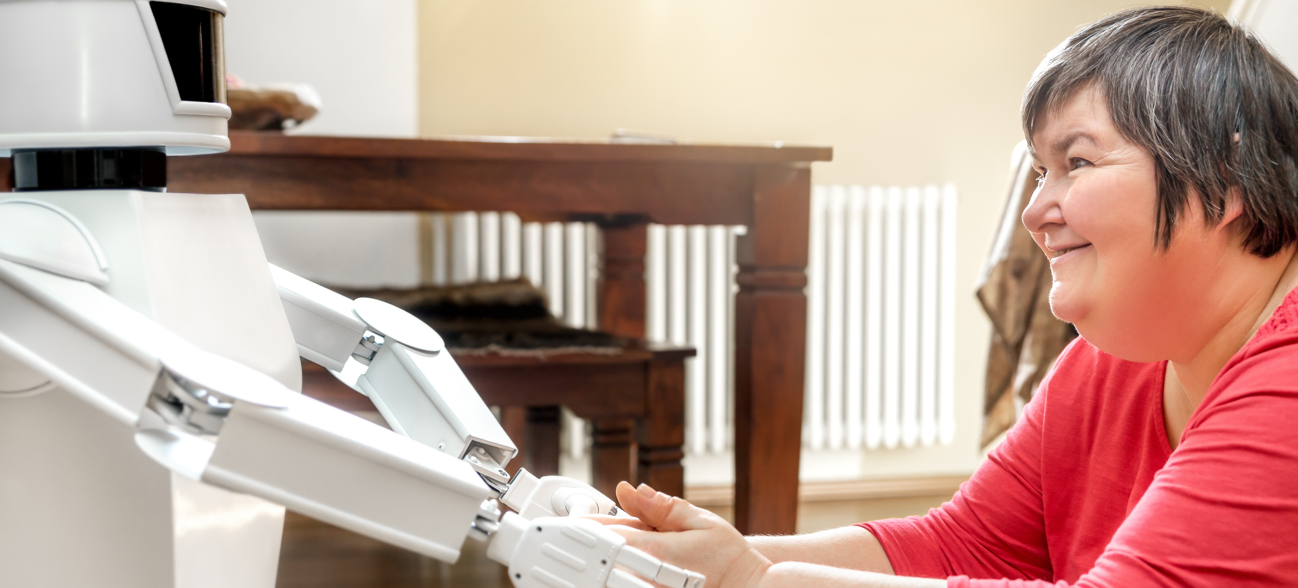 [Hauptbild] Ein mit künstlicher Intelligenz entwickelter Roboter umarmt die Hände einer lächelnden, hilfsbedürftigen Person.
