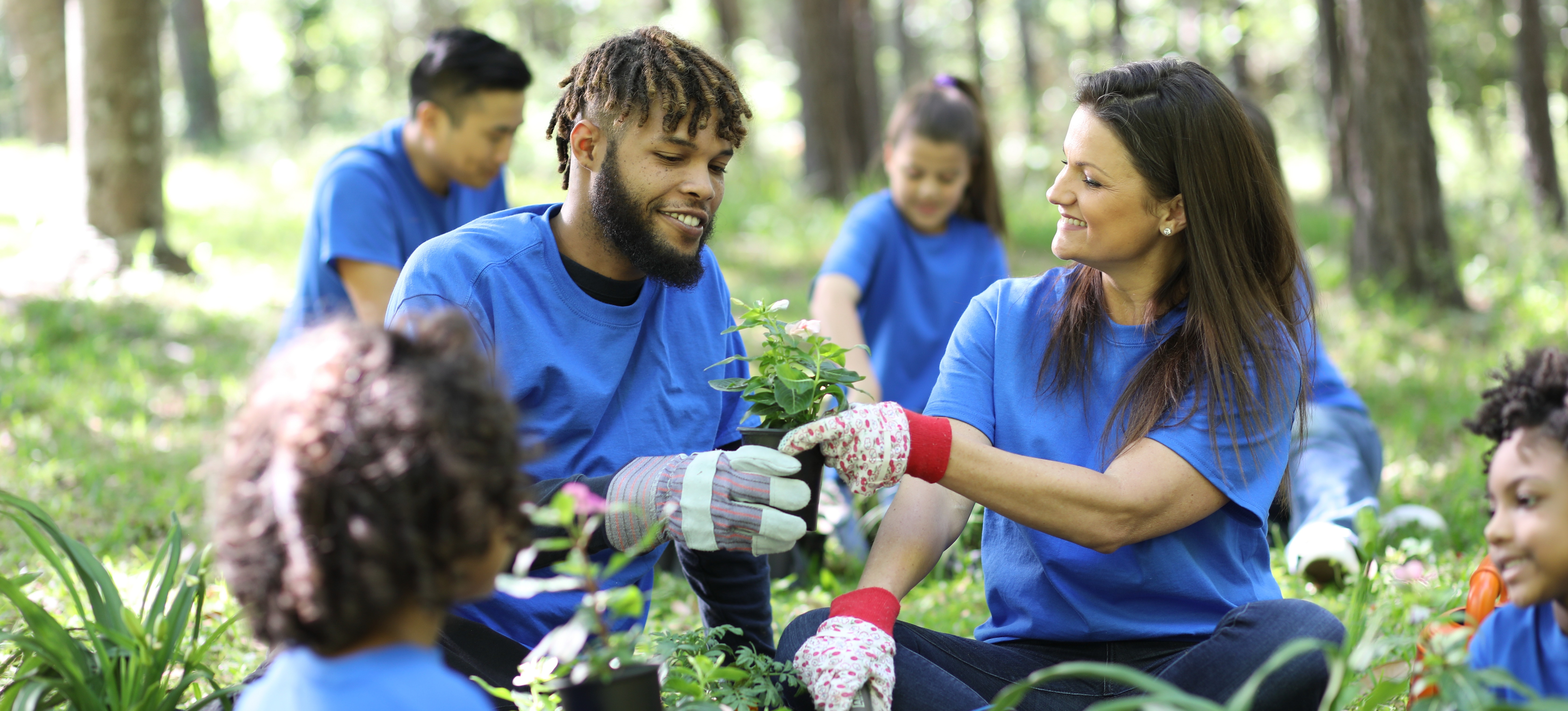 [Featured Image] A group of volunteers planting trees, smiling, and discussing environmental sustainability skills.
