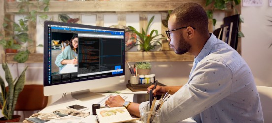 [Featured image] A web designer sits at his desktop computer working on a webpage design.