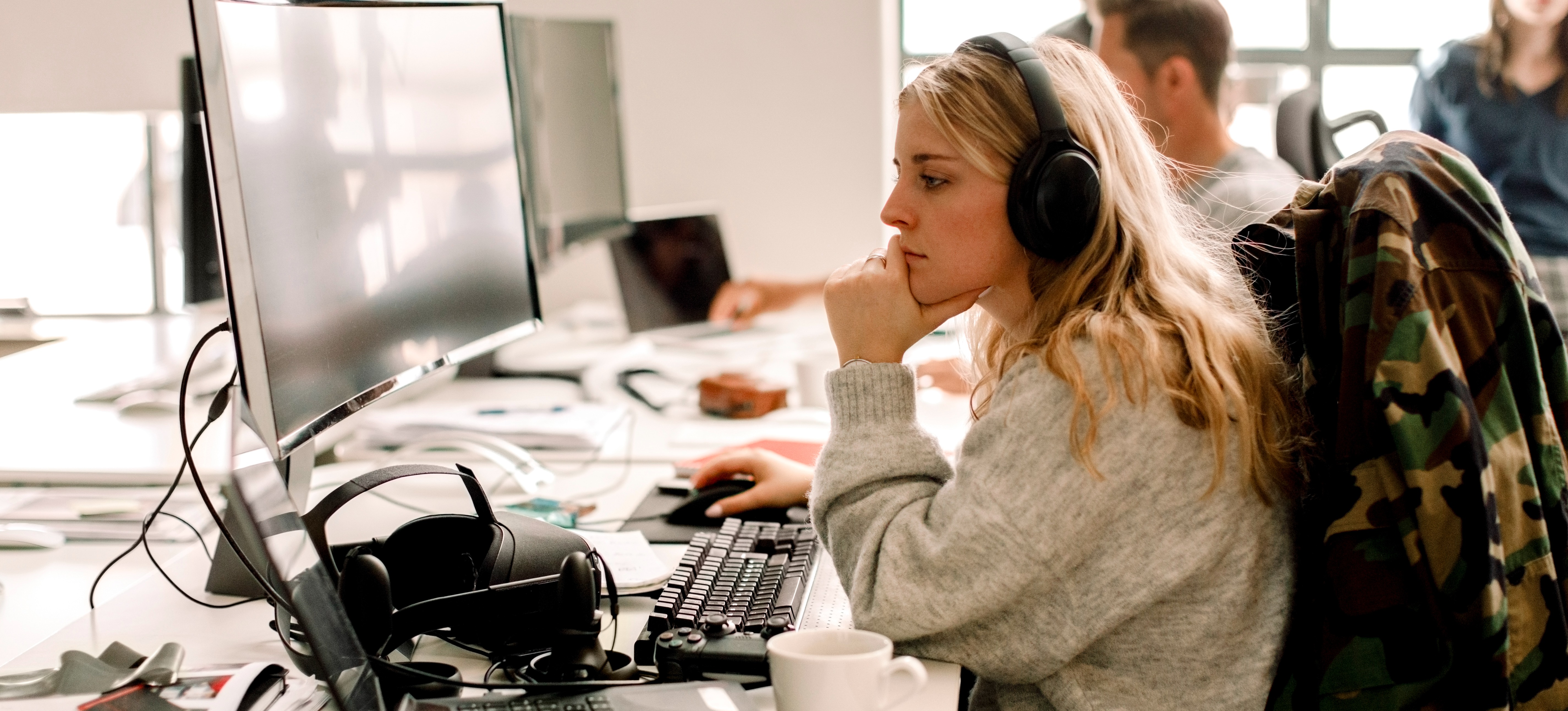 [Feature Image] A learner wearing headphones and working at a desktop computer experiments with Gang of Four design patterns as part of their coursework. 
