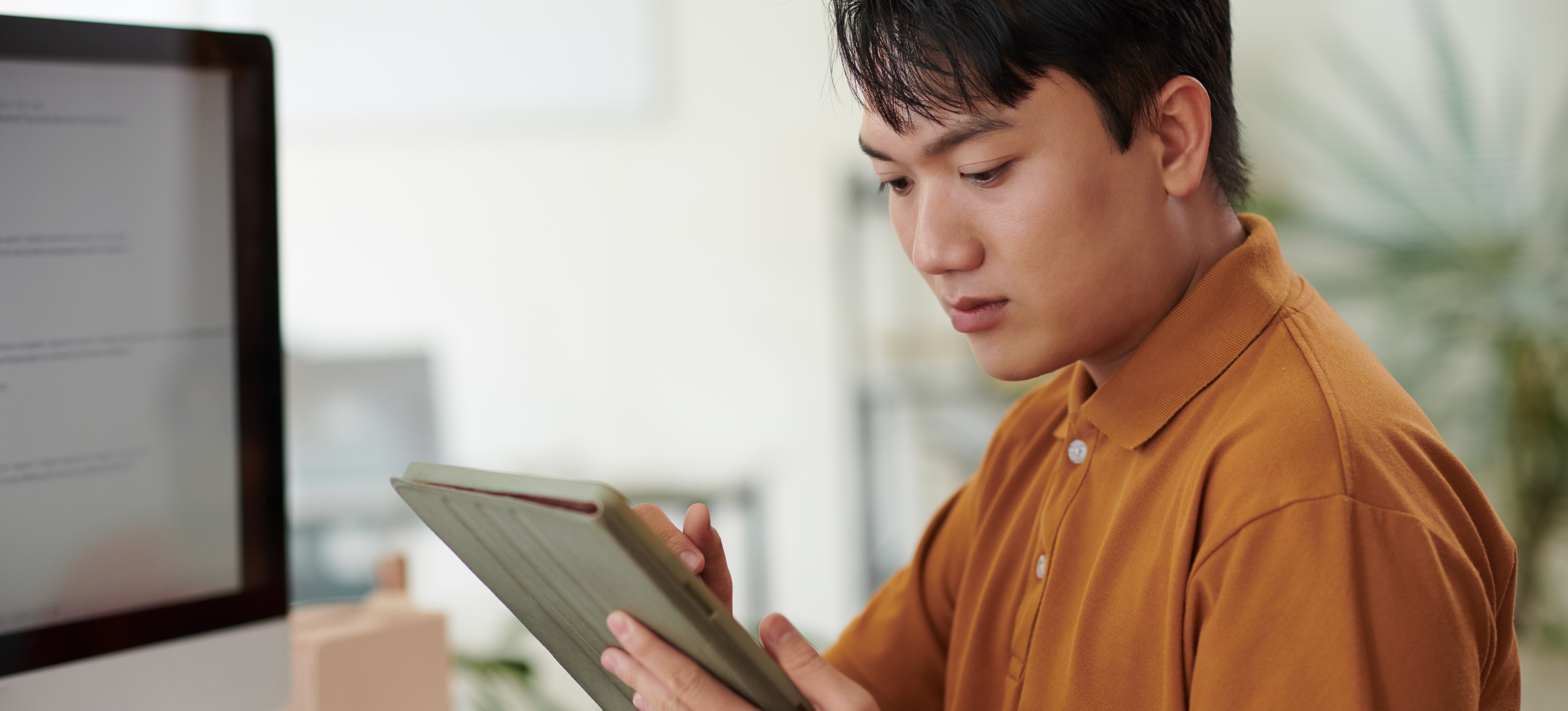 [Featured Image] A data science professional sits at a desk with a computer and tablet, using the random forest algorithm to aggregate data.