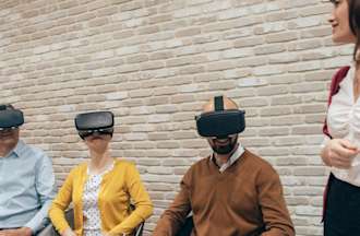 [Featured Image] A group of colleagues sit in a business meeting wearing virtual reality headsets and experimenting with VR, one of the top business intelligence trends of 2024. 
