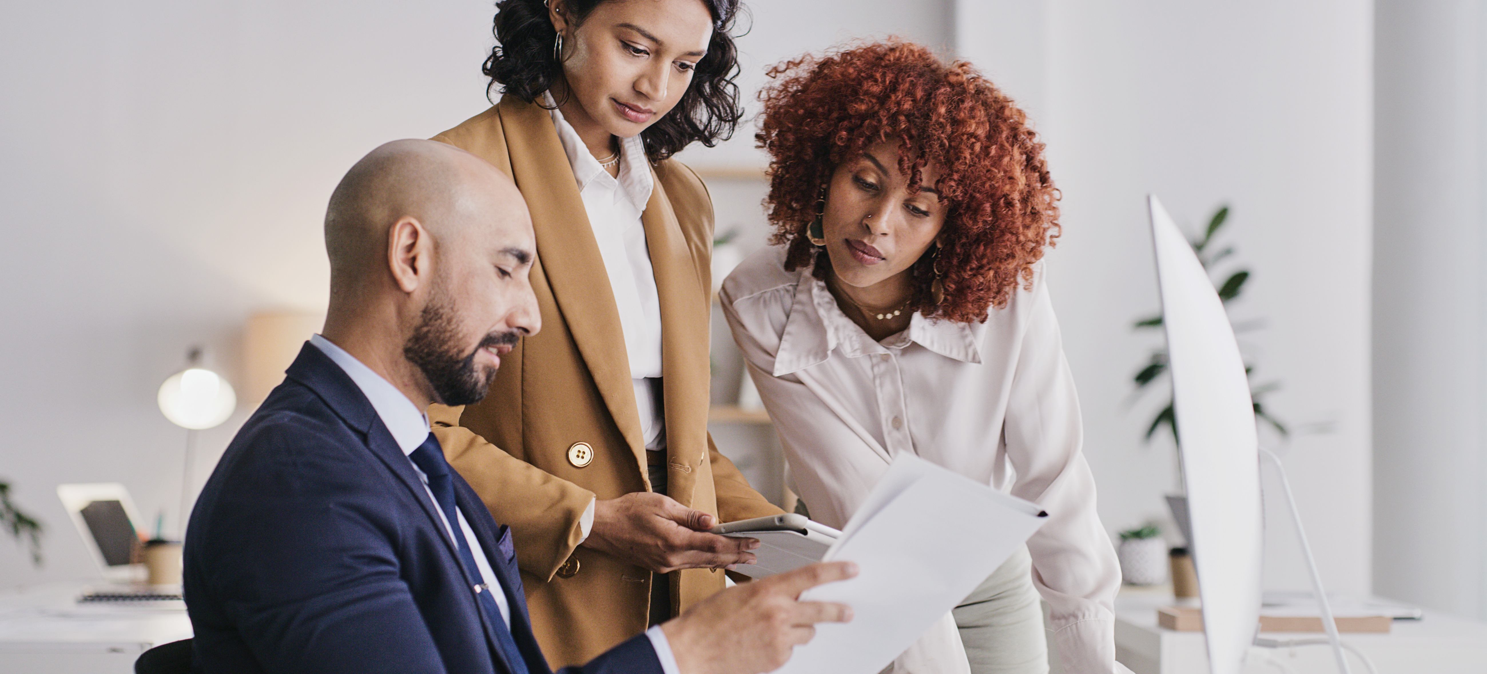 [Featured Image] A group of three business analysts go over a business analysis report before presenting it to their leadership.