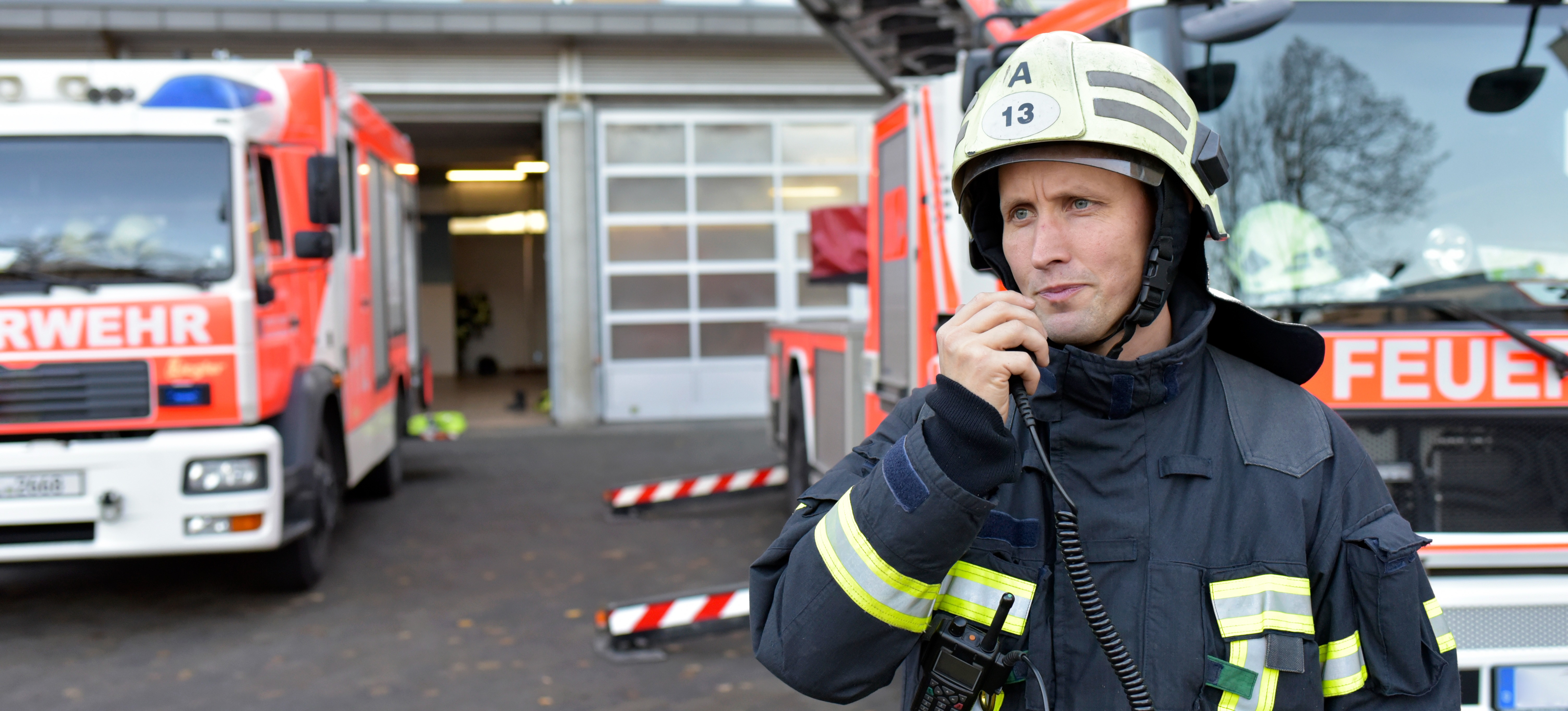 [Featured Image] A firefighter is using a walkie talkie, a half duplex device, to comunicate with his team.
