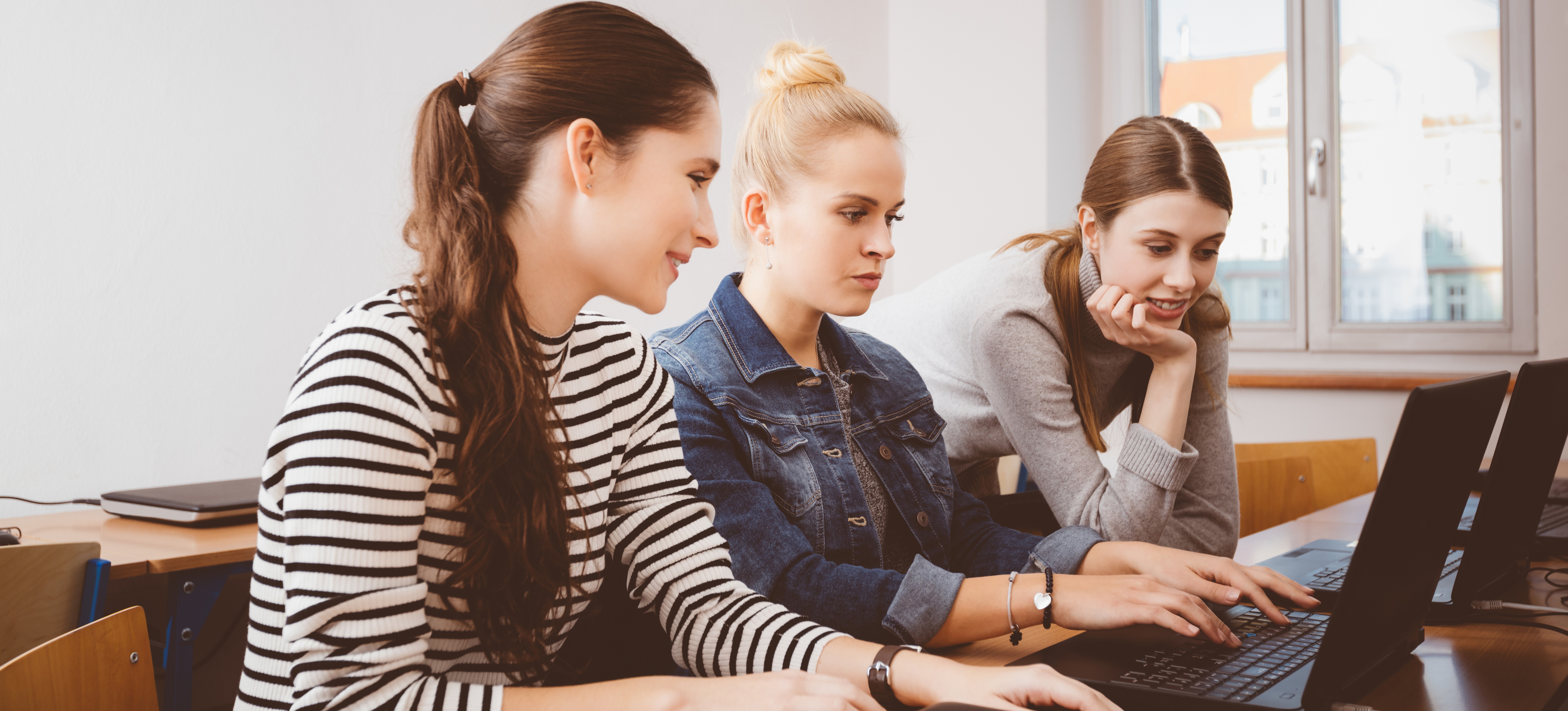 [Featured Image] Three colleagues sit at a workspace, using software configuration management to help streamline their workflow.
