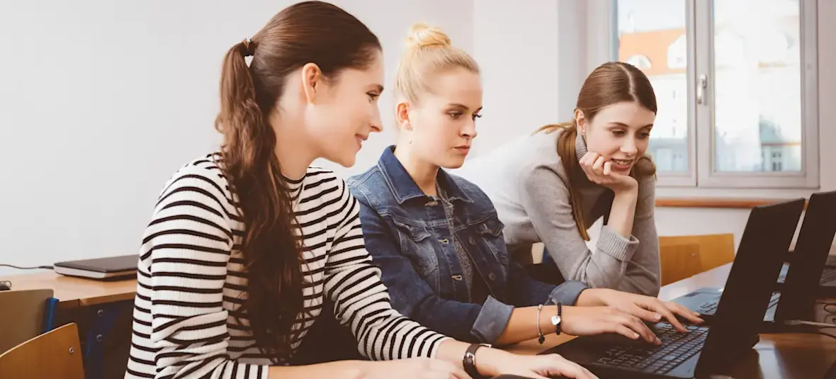 [Featured Image] Three colleagues sit at a workspace, using software configuration management to help streamline their workflow.
