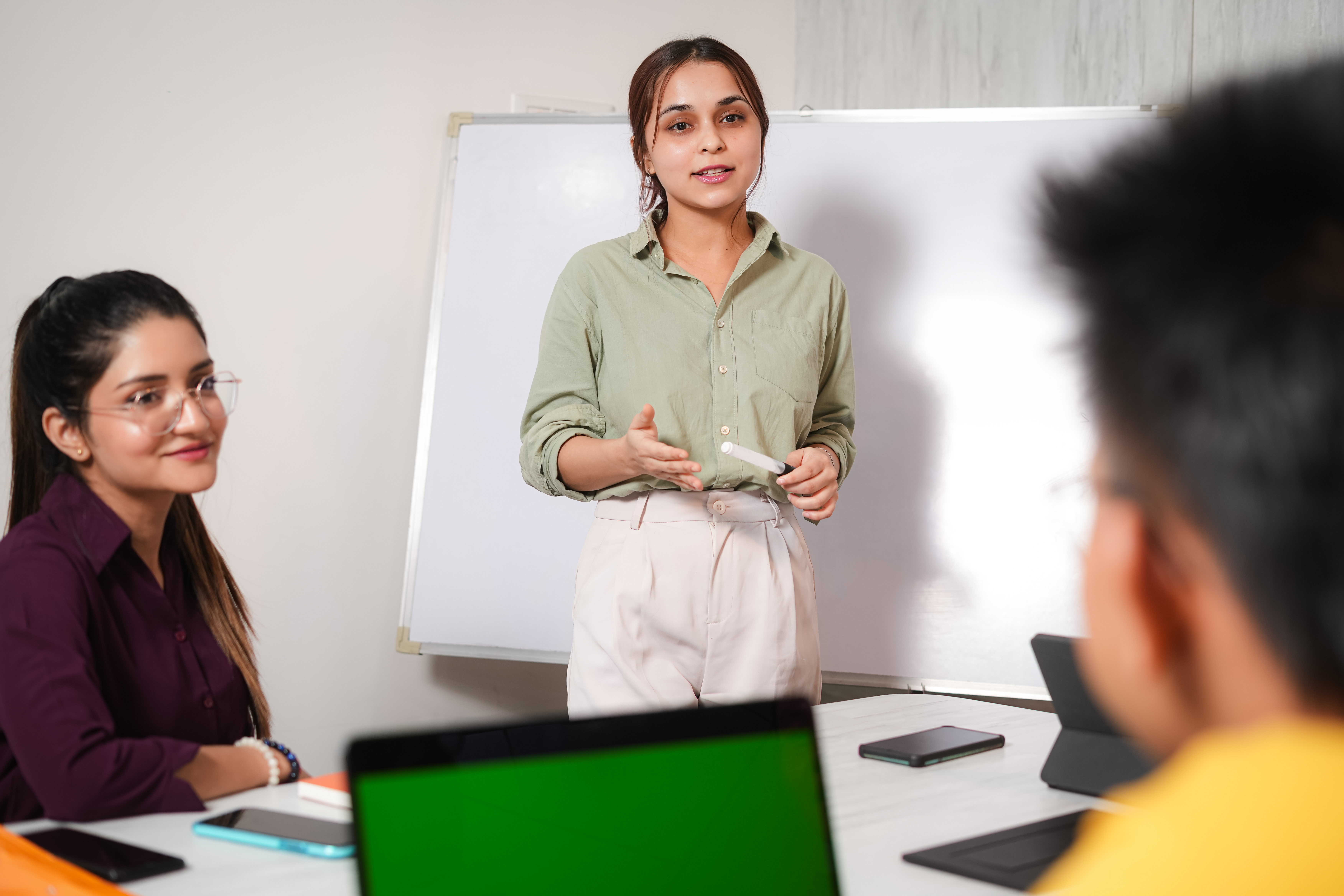 [Featured image] An HR coordinator standing in front of a group of colleagues near a whiteboard during a training session. 