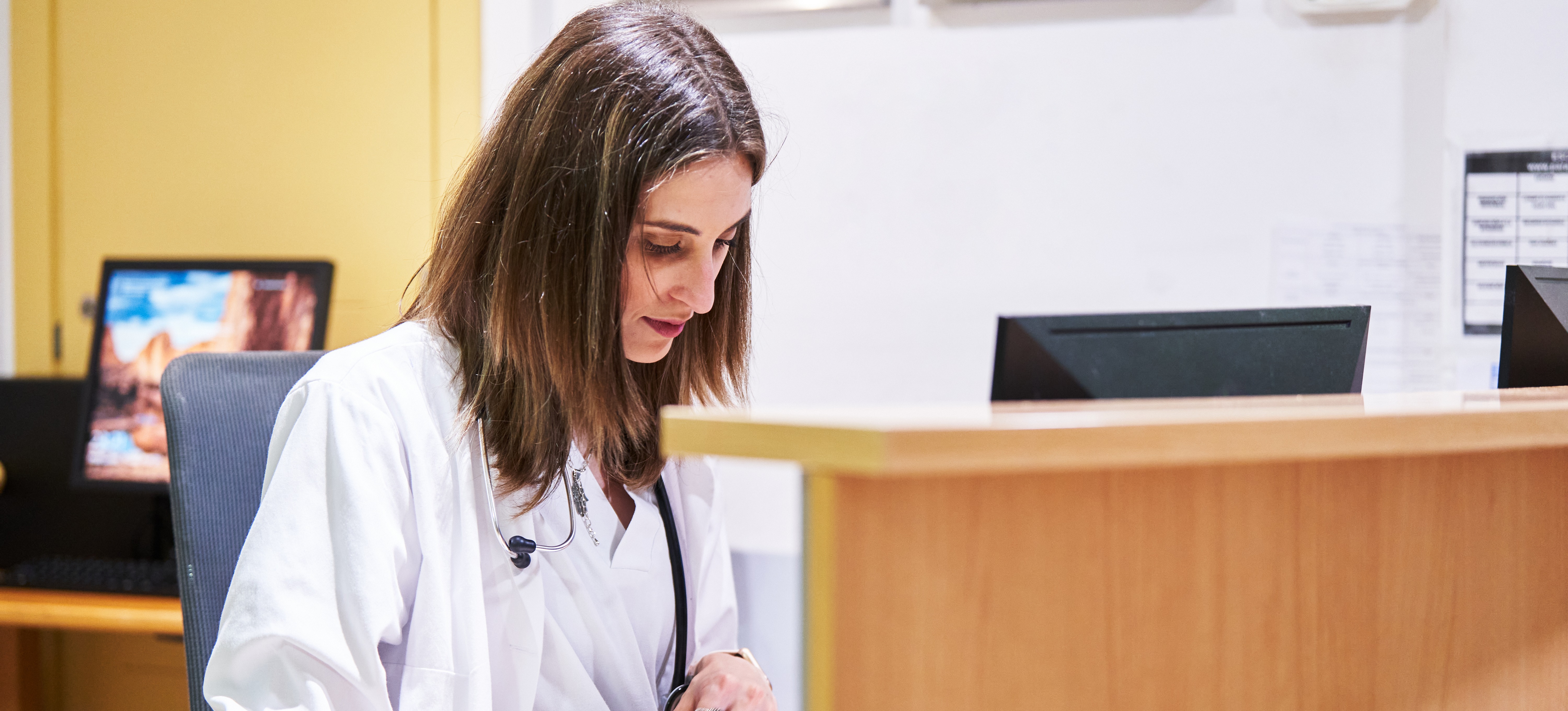 [Featured Image]: A medical records technician sits behind a desk in a medical facility and enters patient information into an electronic database.
