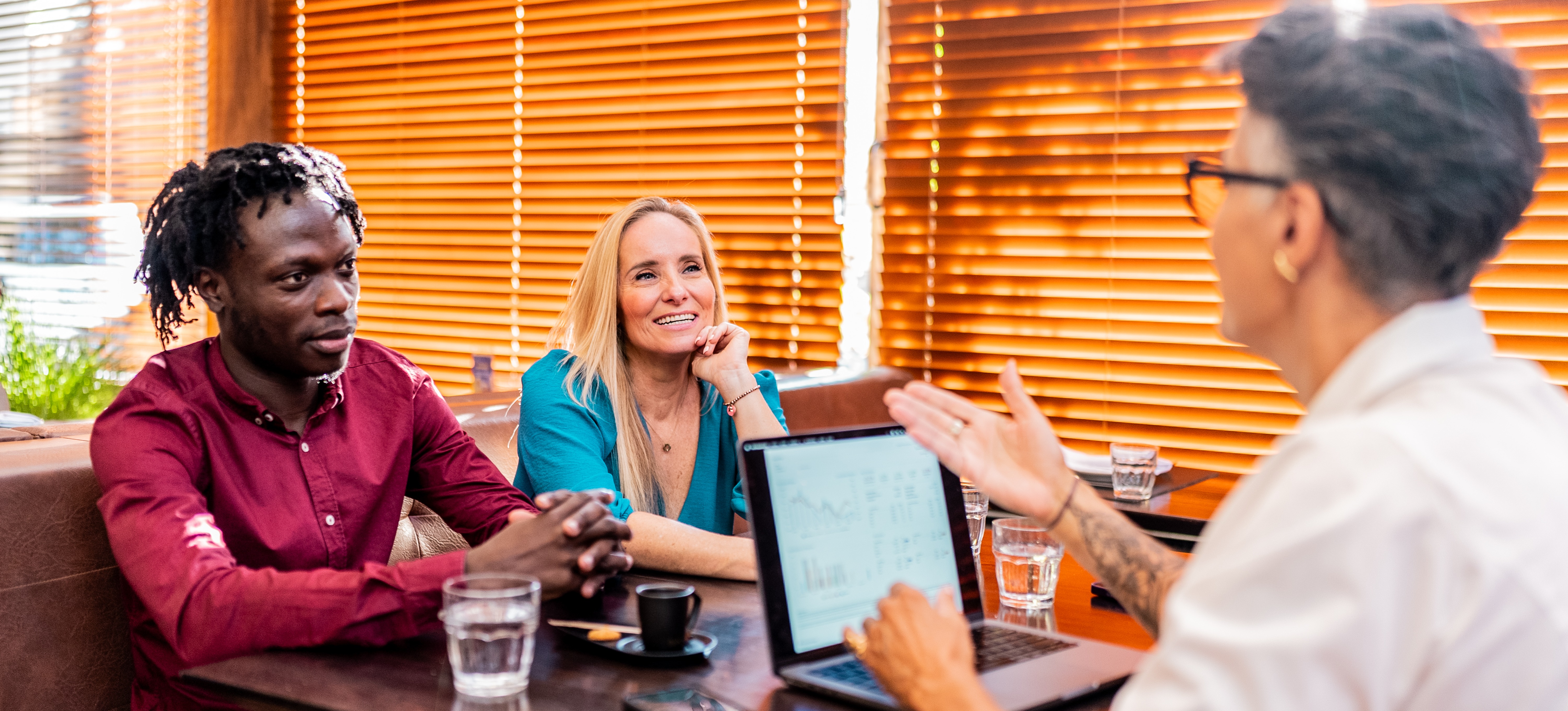 [Featured Image]Three people conducting business in front of a computer. with what might be a spreadsheet open.
