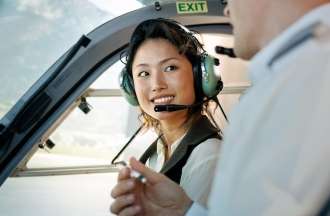 [Featured image] A female trainee pilot listens to her instructor during flight training inside an airplane.
