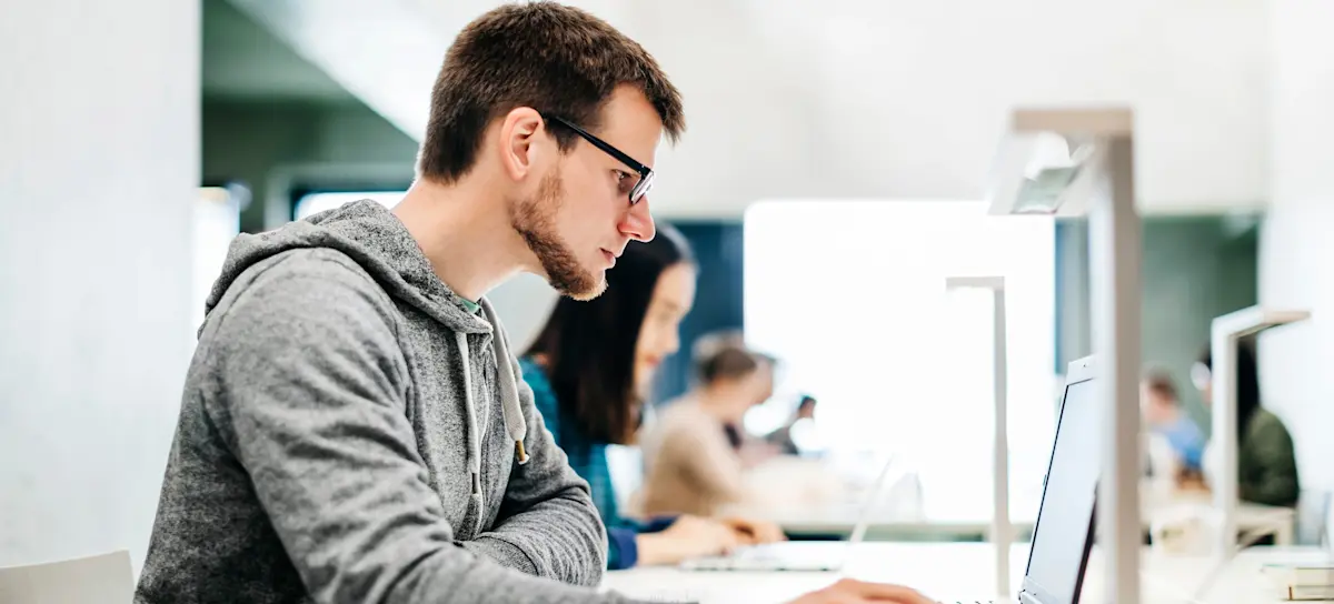 [Featured Image] A person sits in a computer lab and learns how to make an AI chatbot.
