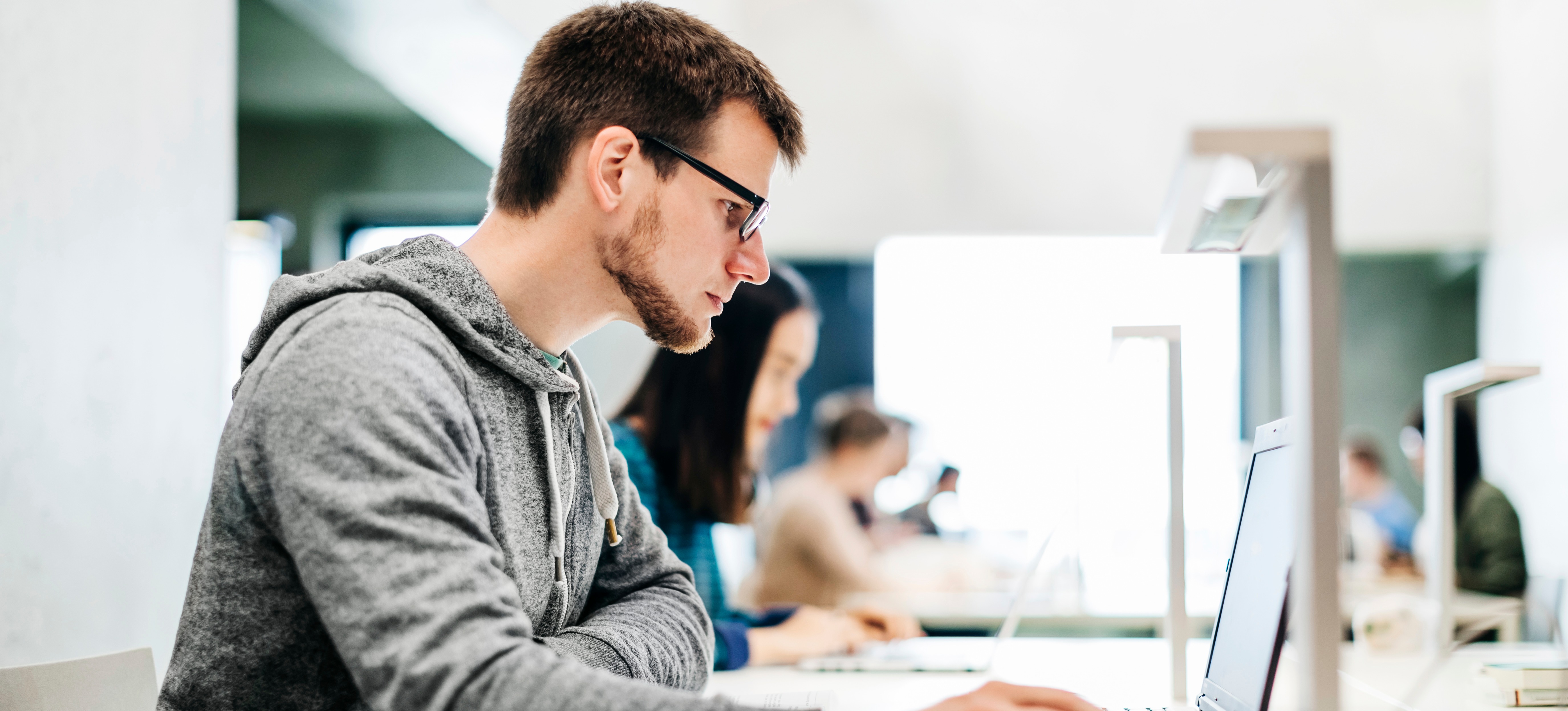 [Featured Image] A person sits in a computer lab and learns how to make an AI chatbot.
