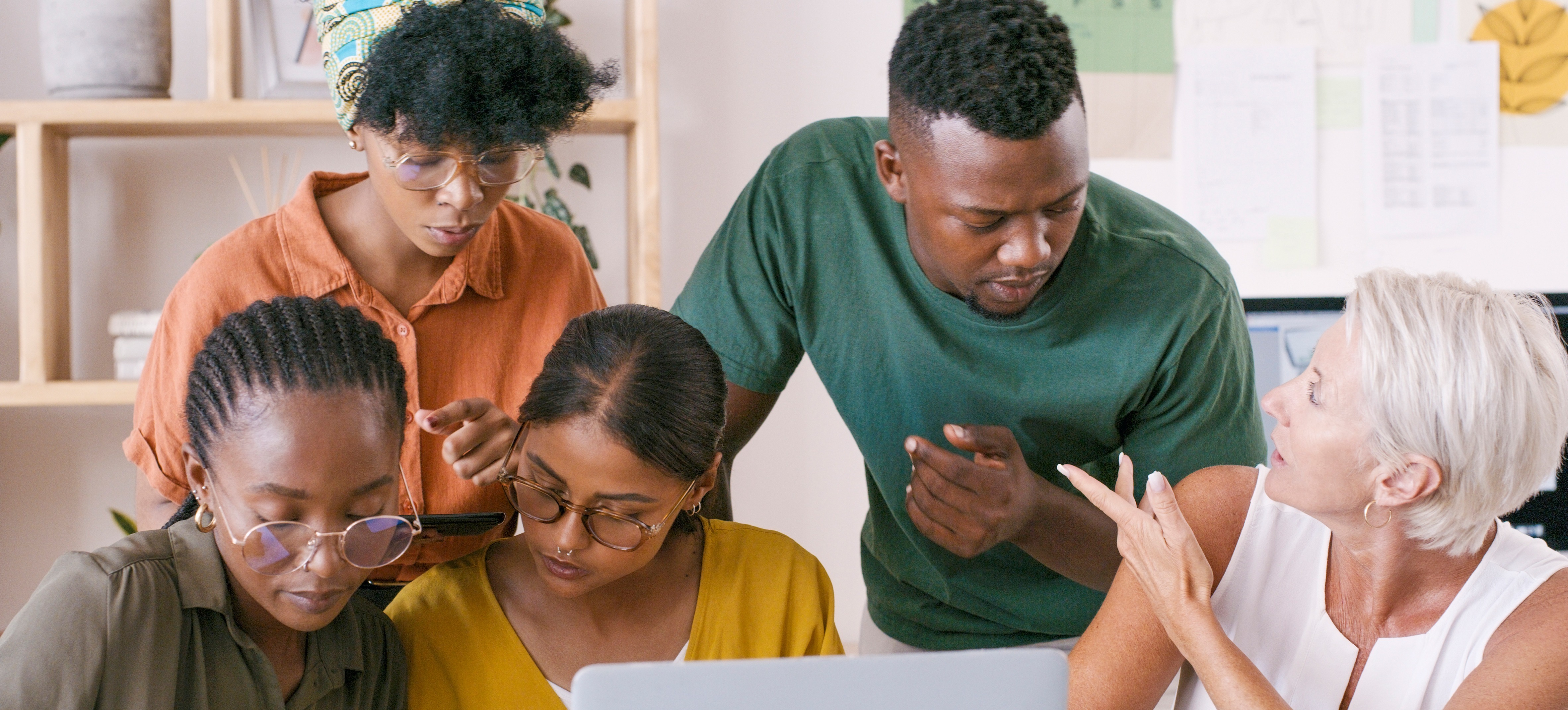 [Featured Image] Small group of people using both a computer and a smartphone app to complete their work.
