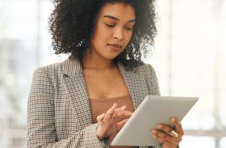 [Featured Image] A human resources professional looks at HR analytics on her tablet.