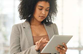 [Featured Image] A human resources professional looks at HR analytics on her tablet.