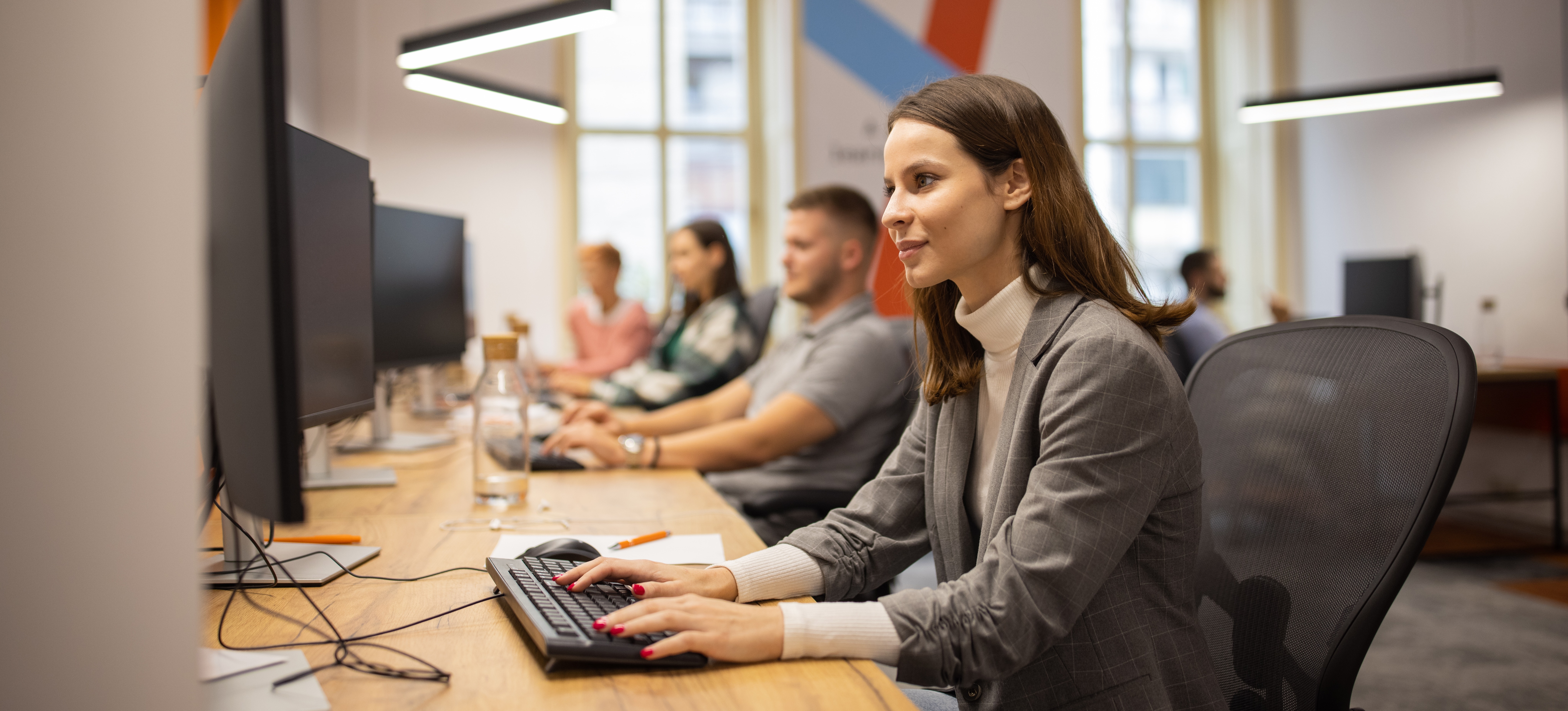 [Image en vedette] Une femme travaille dans un bureau et réfléchit aux avantages et aux inconvénients de sa carrière dans la cybersécurité.