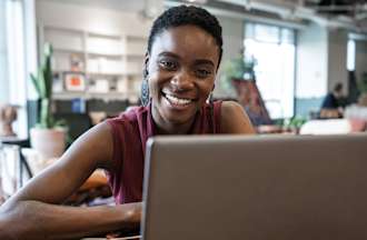 [Featured image] A master's in computer science student sits at a desk in a public space working on her laptop computer.