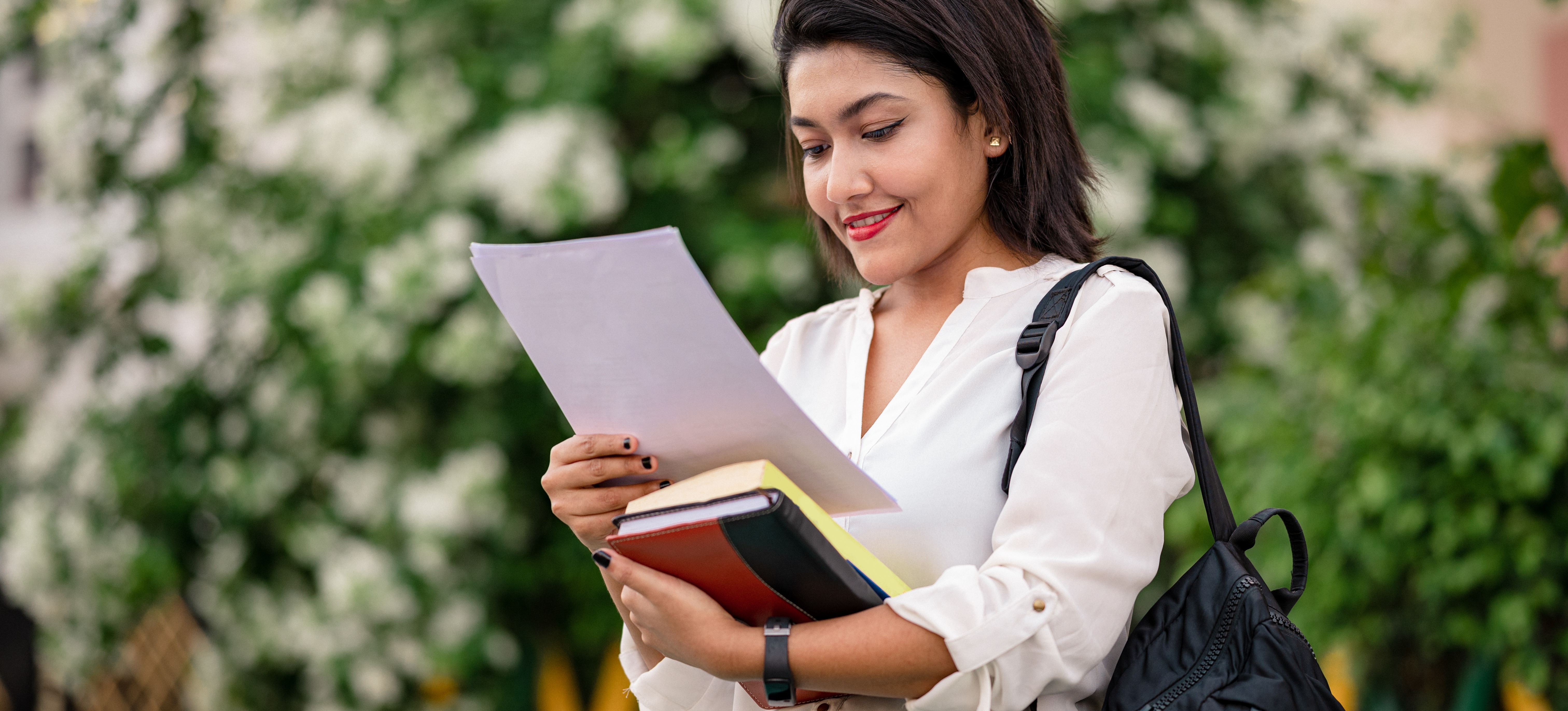 [Featured image] A business degree student prepares reviews materials for the CAT exam while walking on campus.