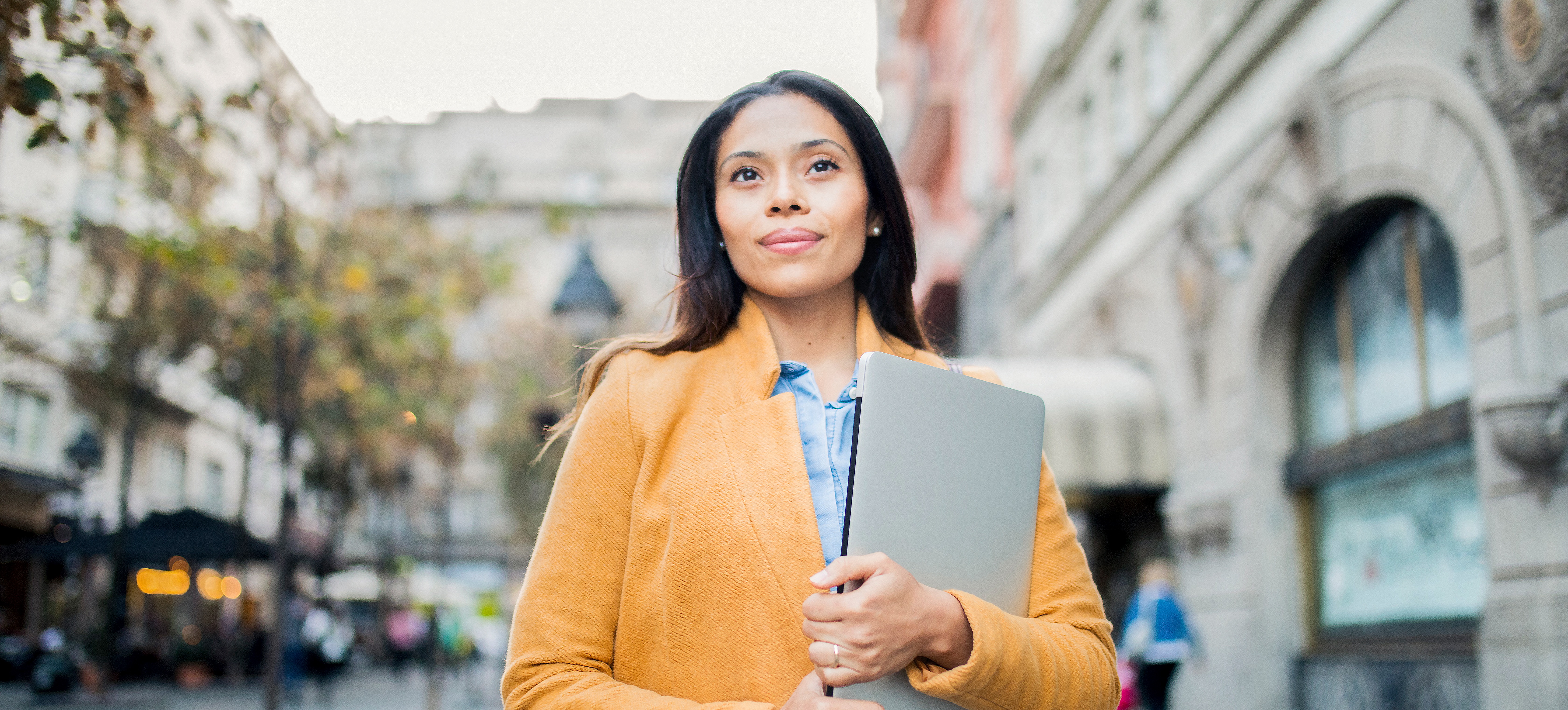 [Featured image] A smiling person who works in public health is standing outside an administration building.